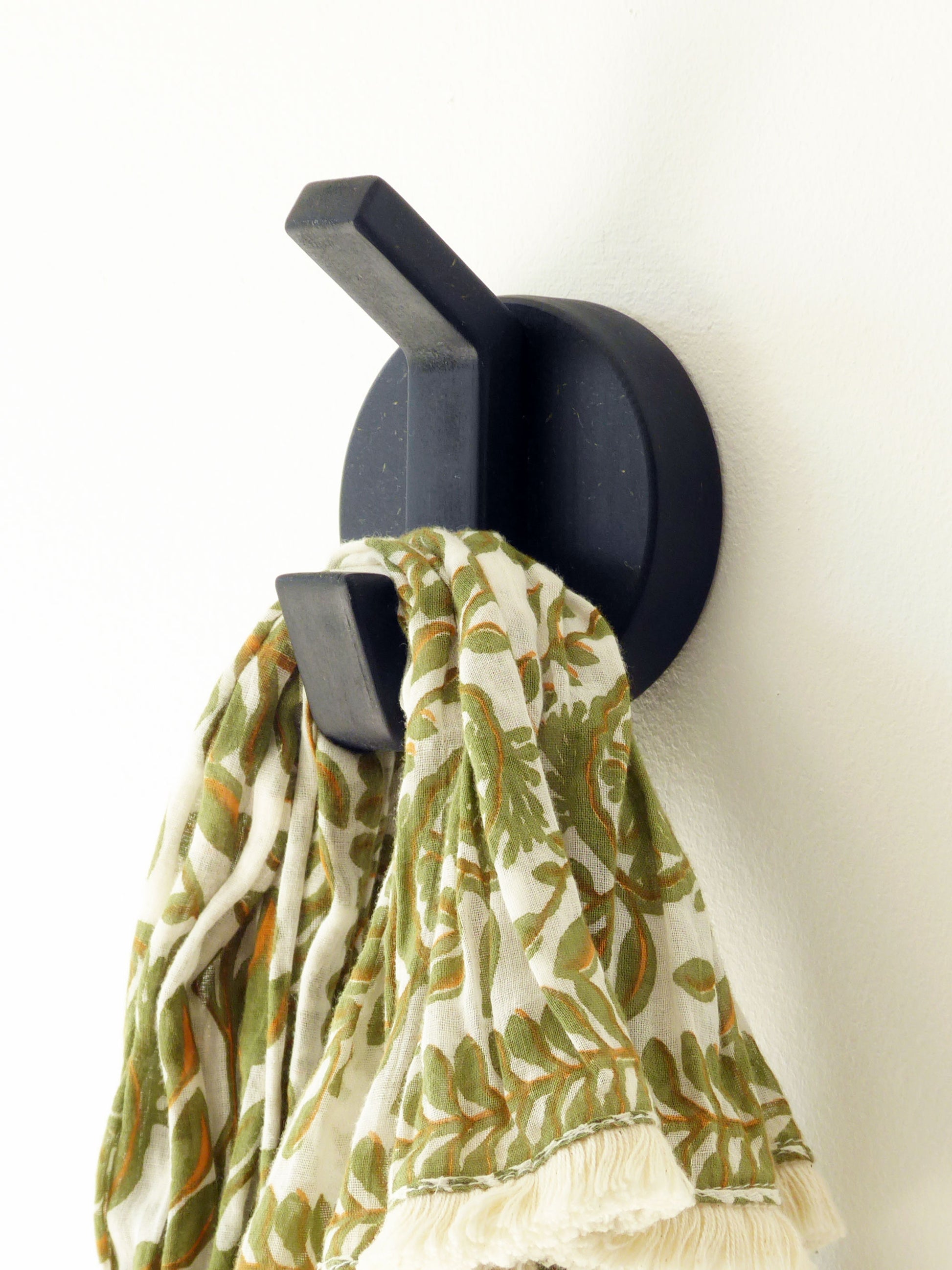 Modern black wall mounted robe hook with a floral scarf hanging from it