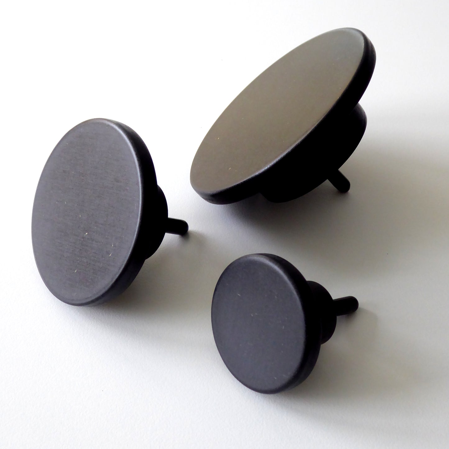 Round minimalist wall hooks in black wood shown in 3 sizes