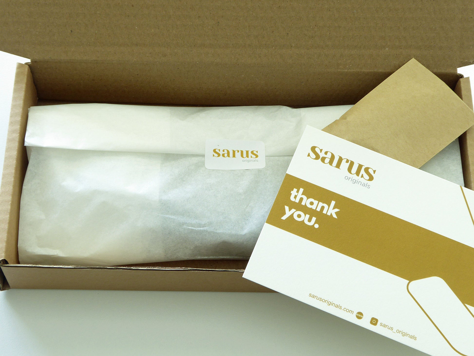 Box showing a tissue wrapped parcel and thank you note