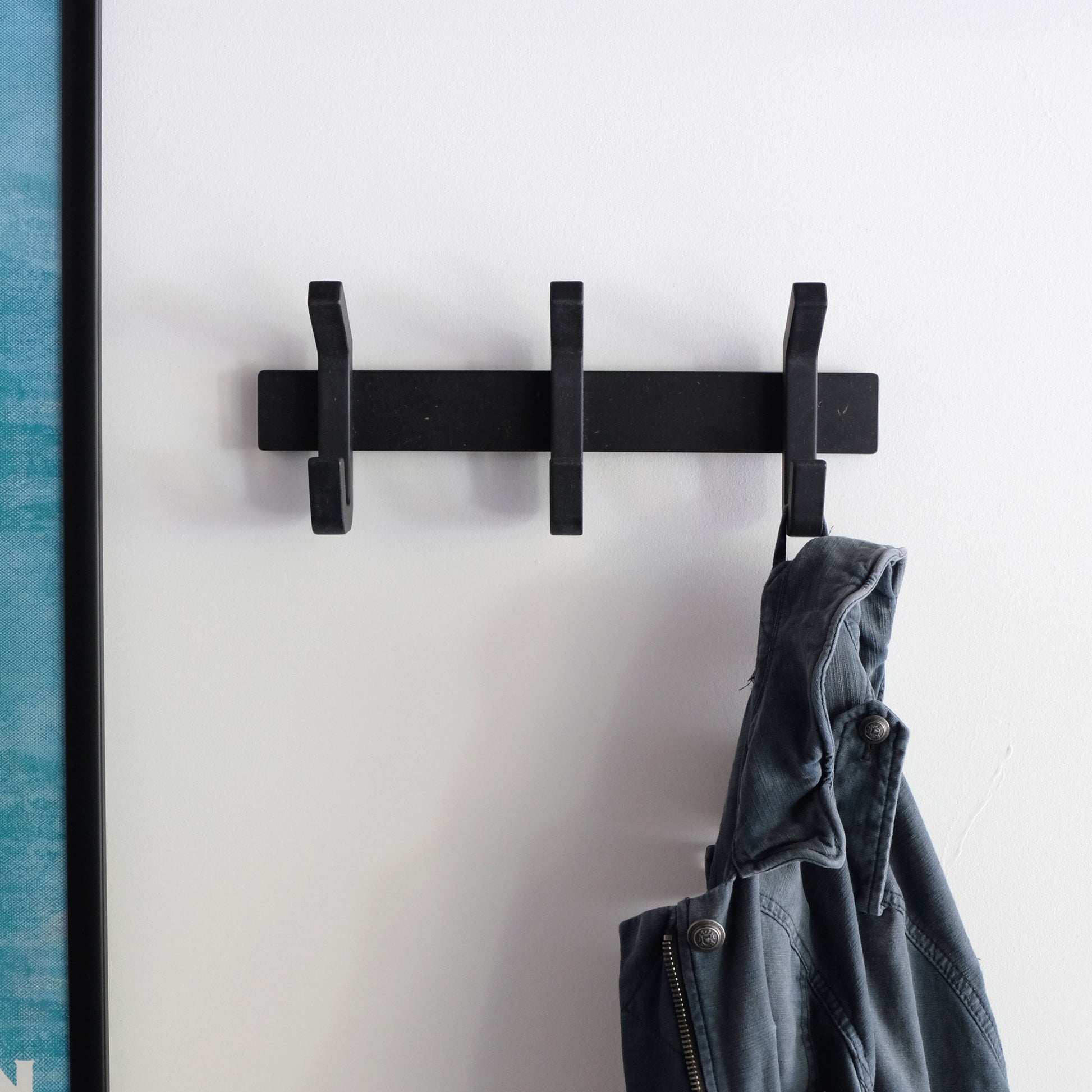 Matt black wooden coat rack hanging in a hallway