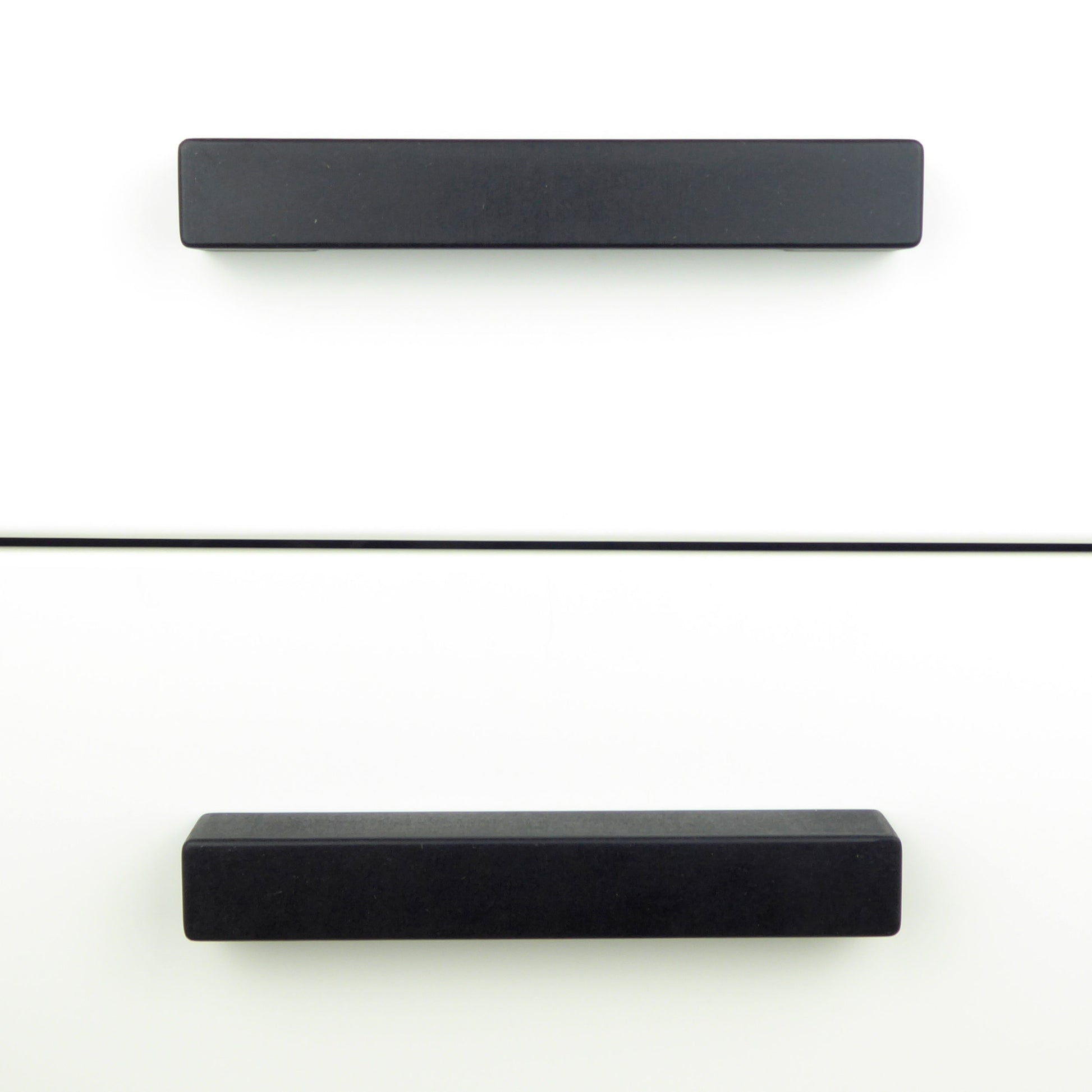 Black wooden drawer pulls in a minimalist style on a white chest of drawers
