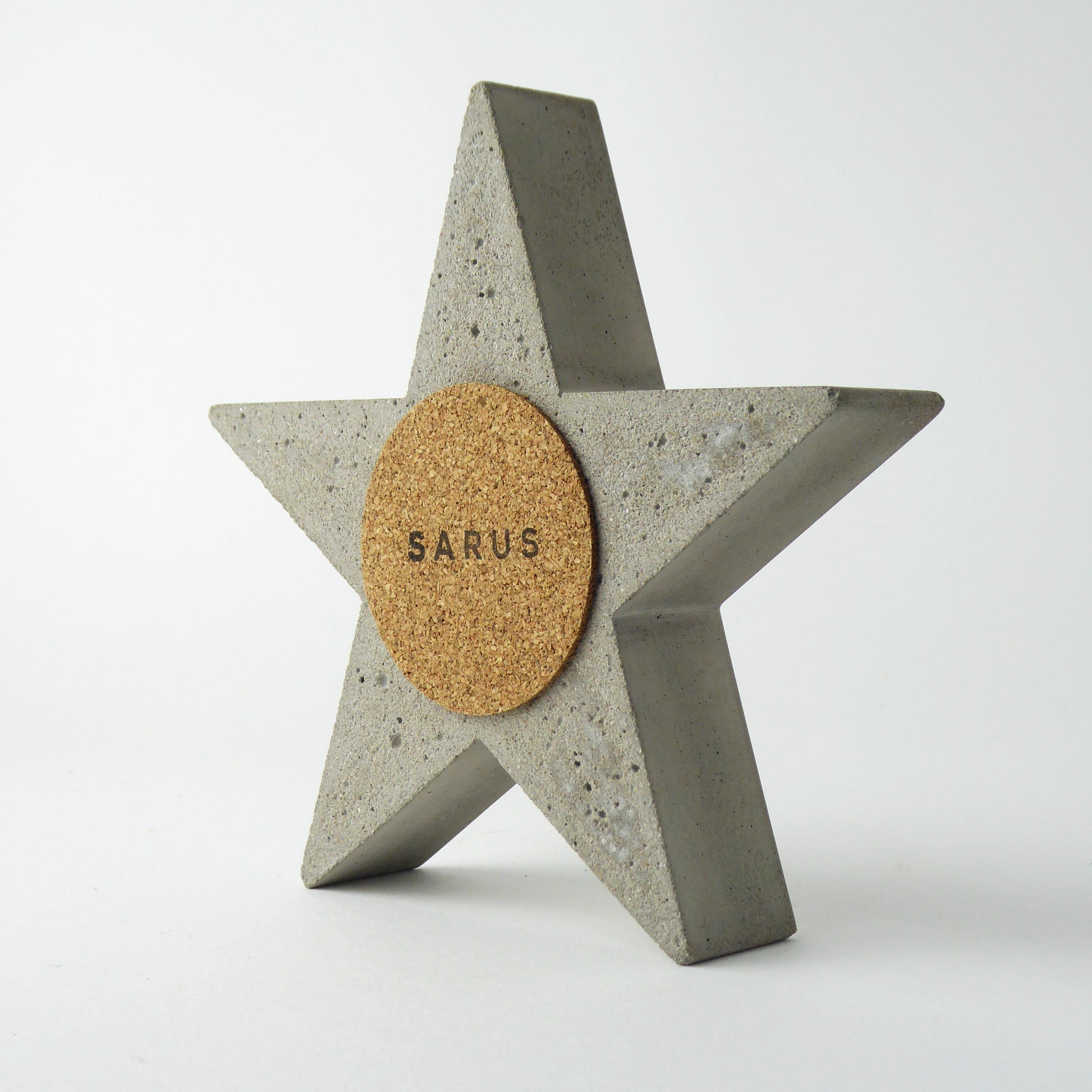 Concrete star-shaped object with a cork back with the logo 'SARUS'