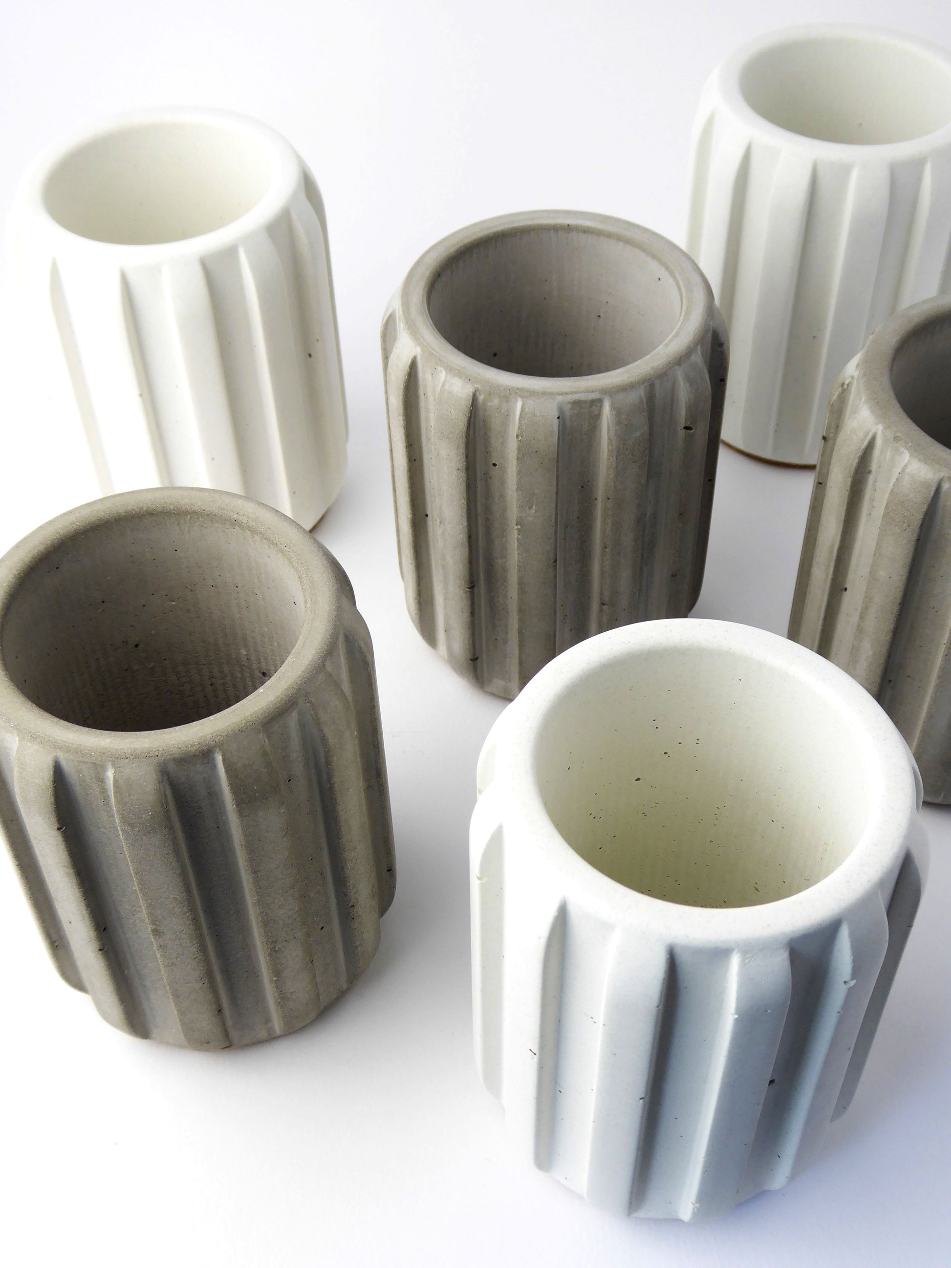 Set of grey and white ceramic pots with ribbed textures on a white background