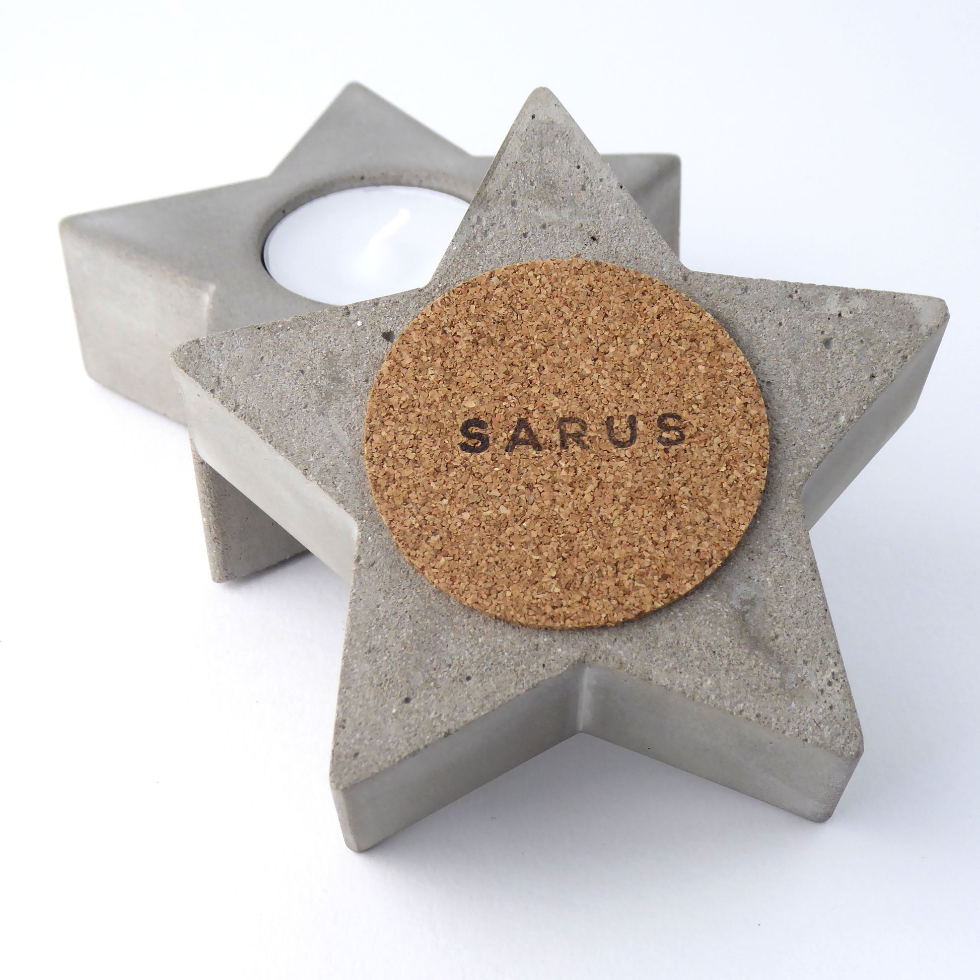 Star-shaped concrete candle holder with cork base and 'SARUS' logo on a white background
