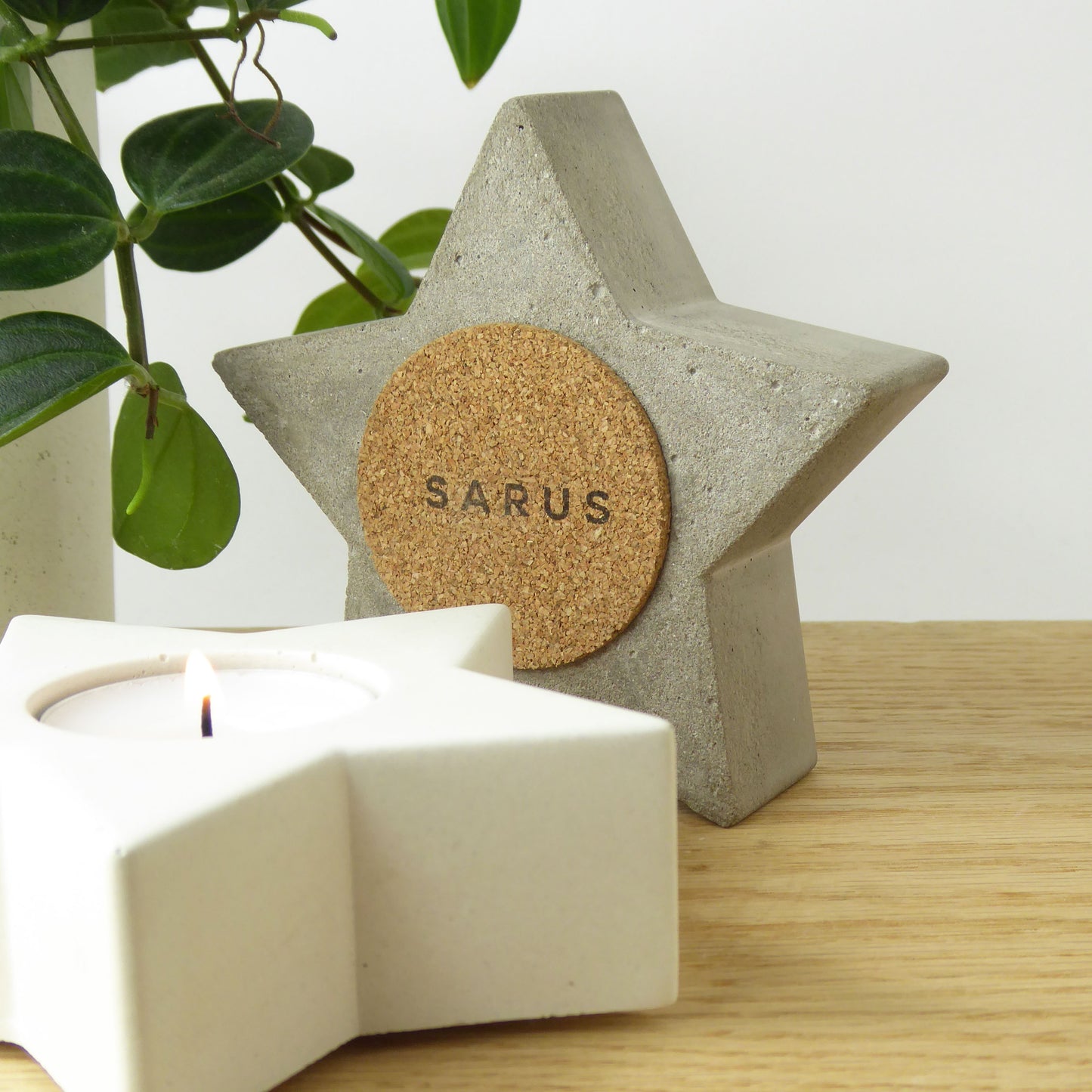 Star-shaped concrete candle holder with cork on the underside to protect surfaces and white star candle on a wooden shelf