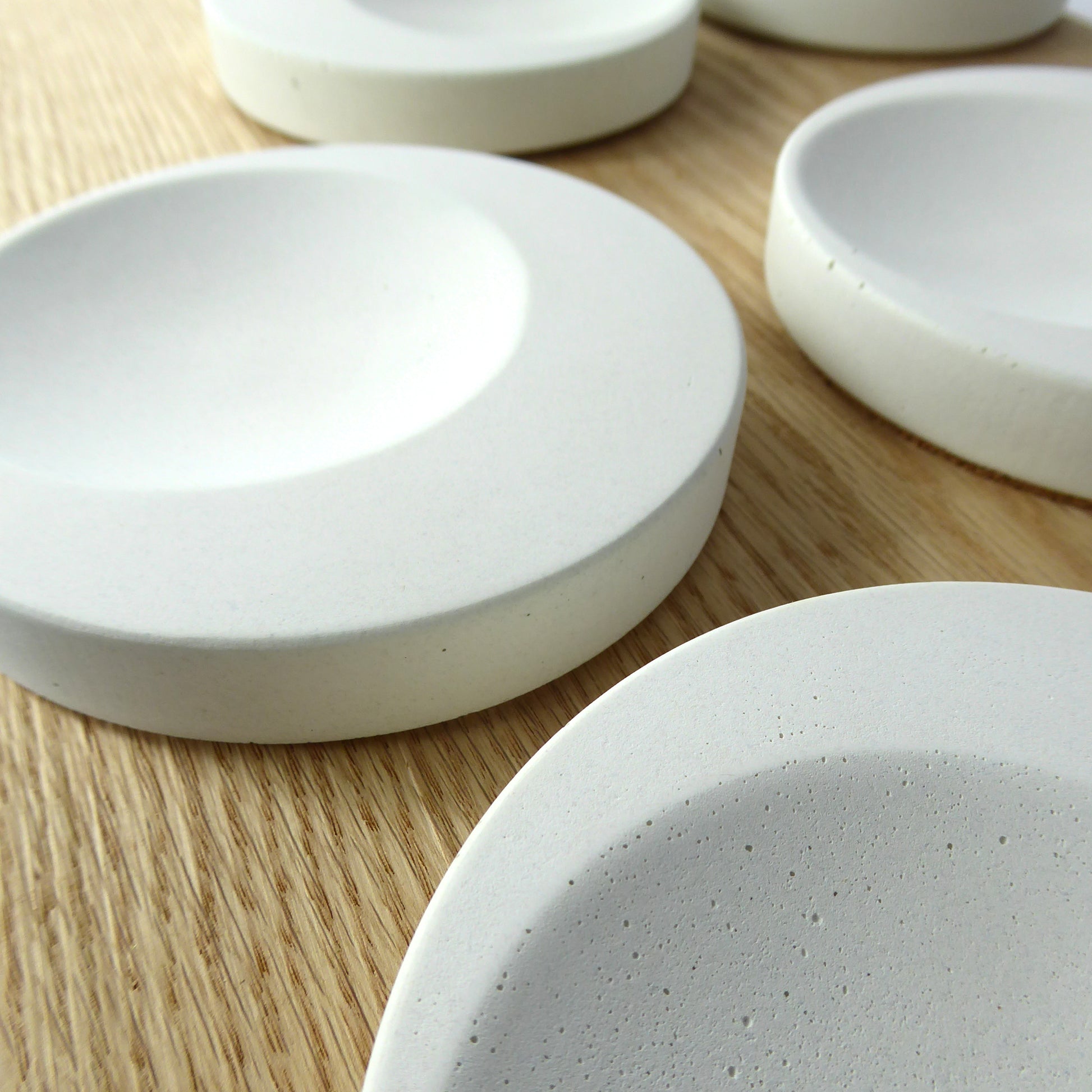 Round decorative dishes in white concrete on a wooden shelf