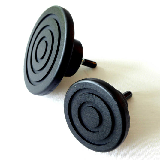 Pair of black round wooden wall hooks with an embossed spiral design, displayed against a white background.