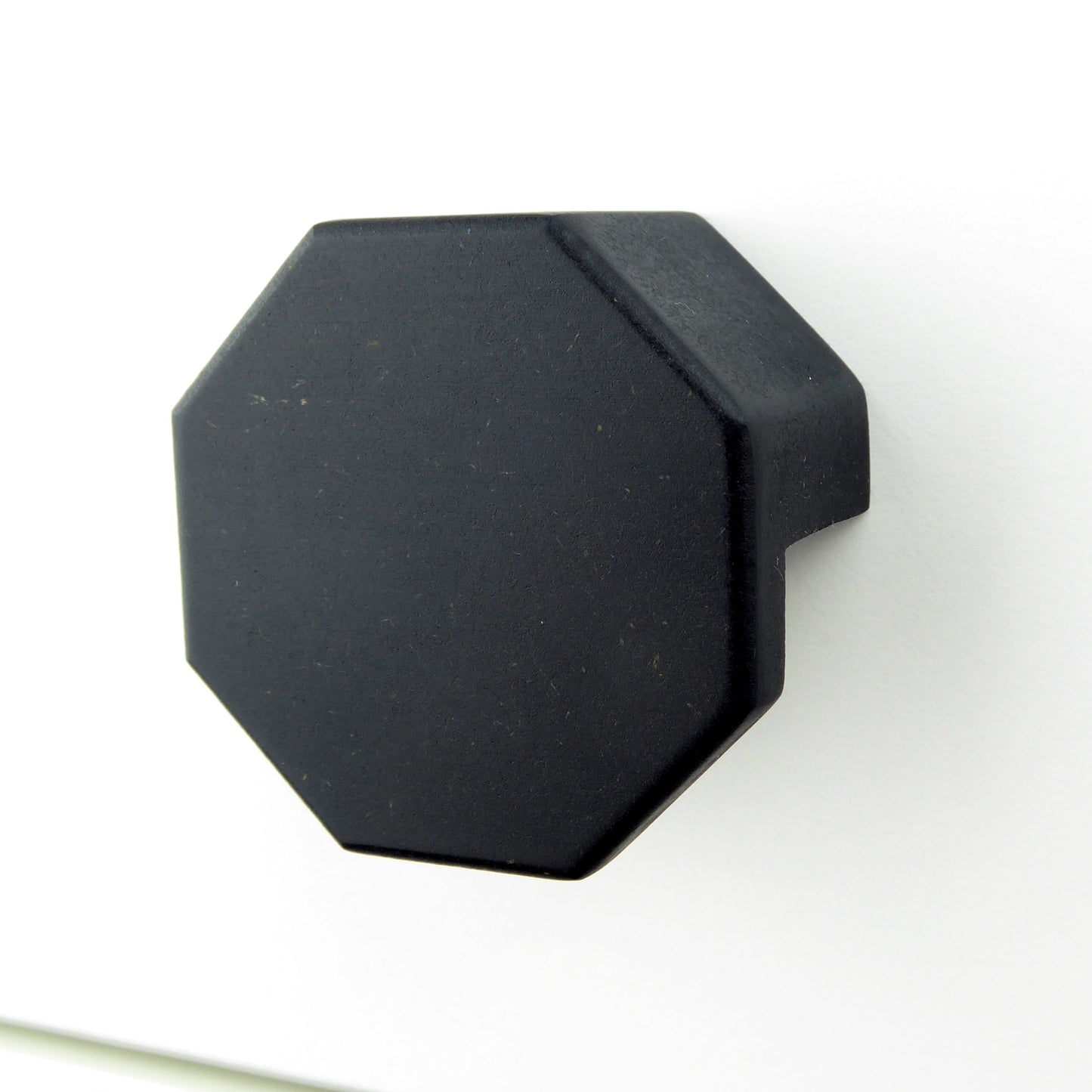 A black hexagon shaped wooden handle for furniture.