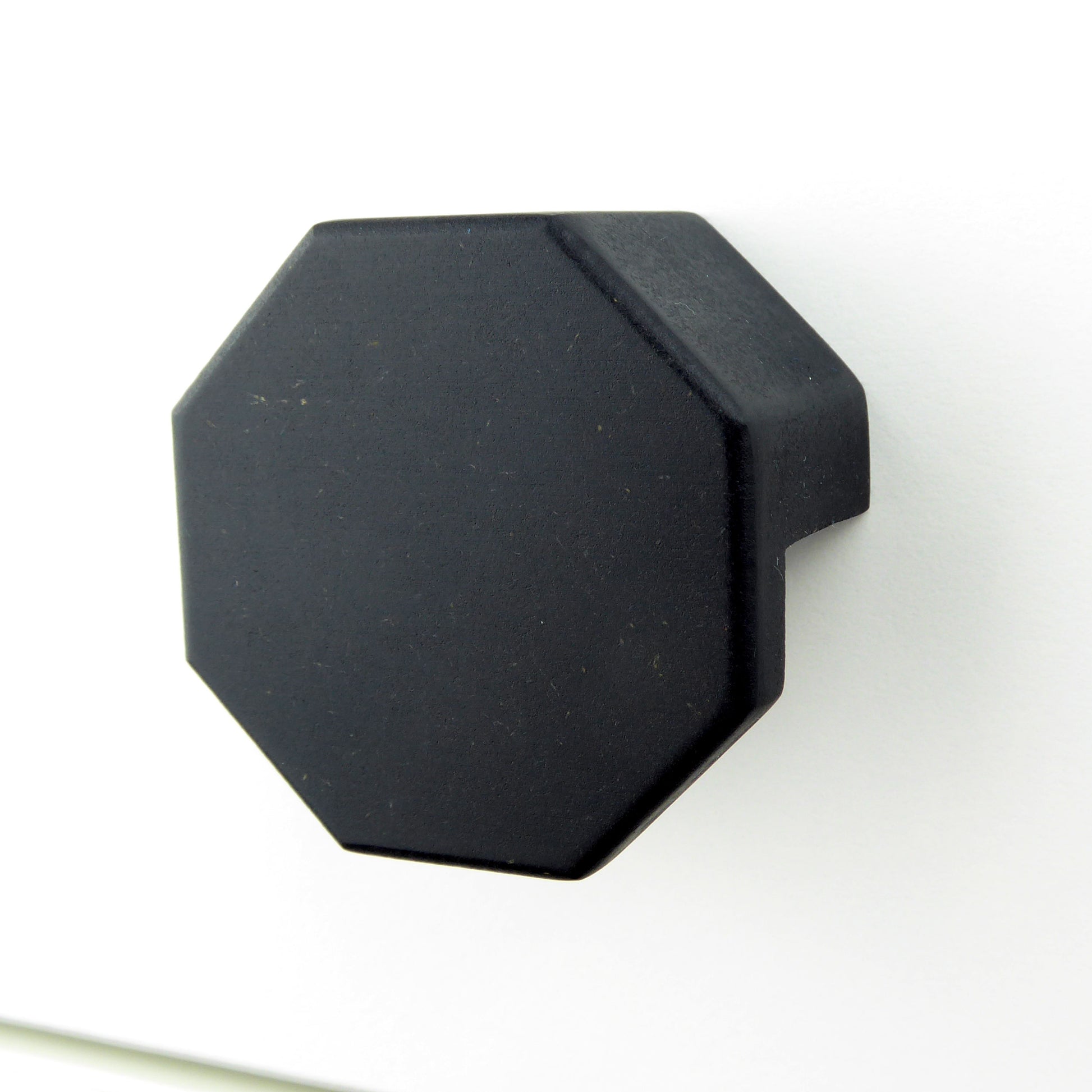 A black hexagon shaped wooden handle for furniture.