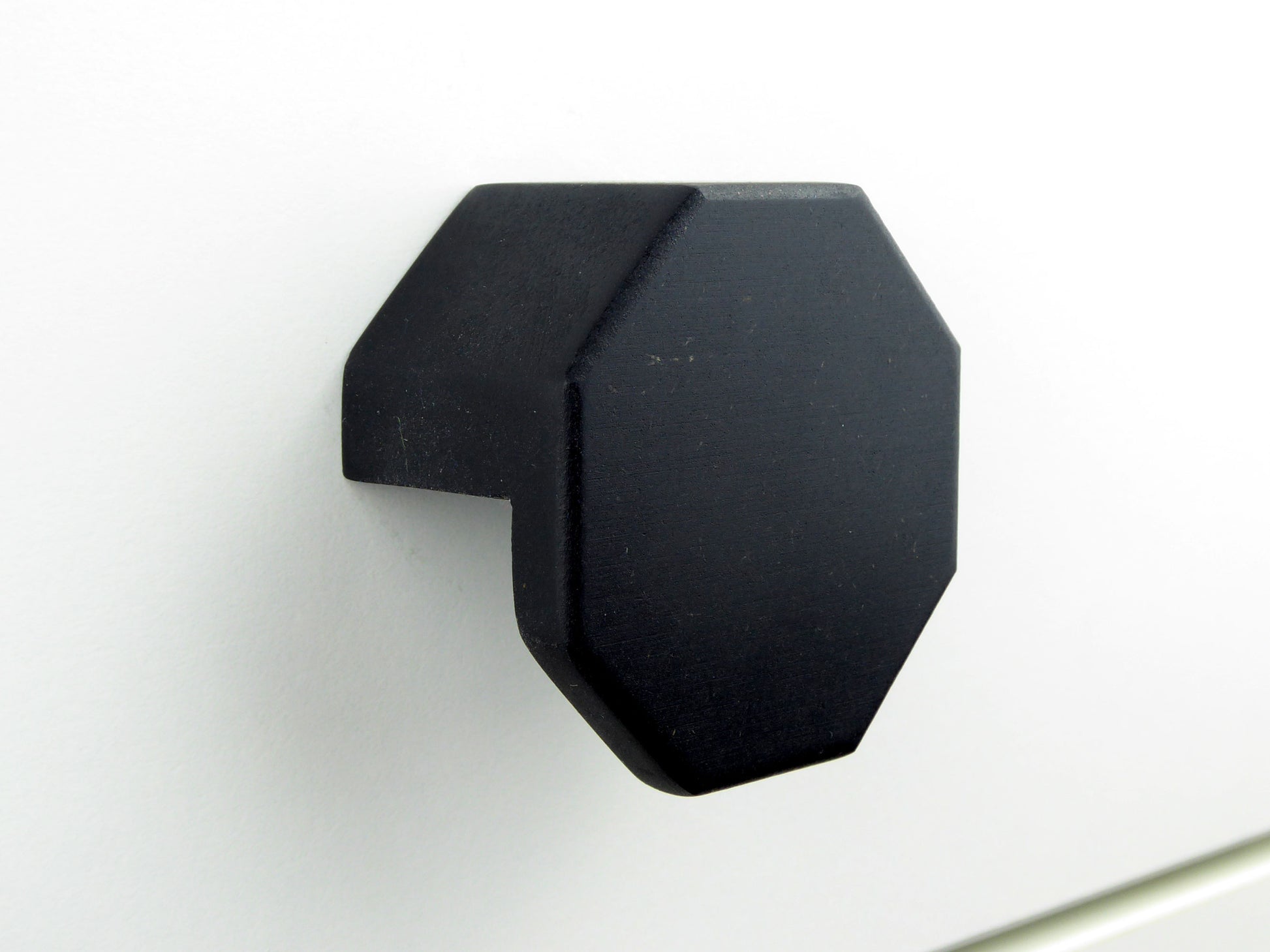 Octagonal pull handle on a kitchen cabinet made from black wood