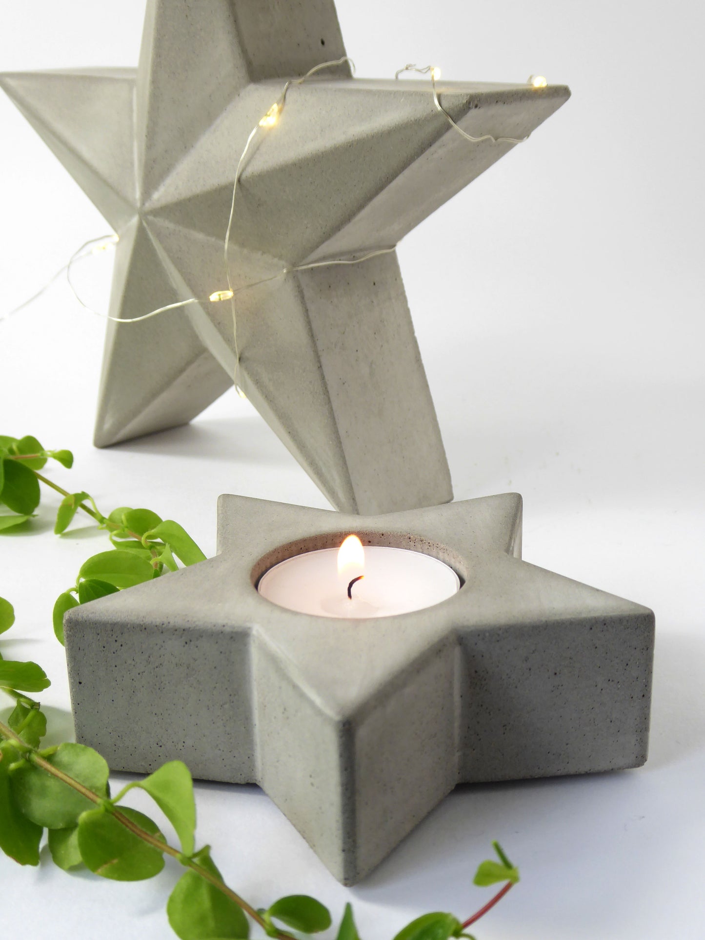 Concrete star-shaped candle holder with a lit candle on a white background