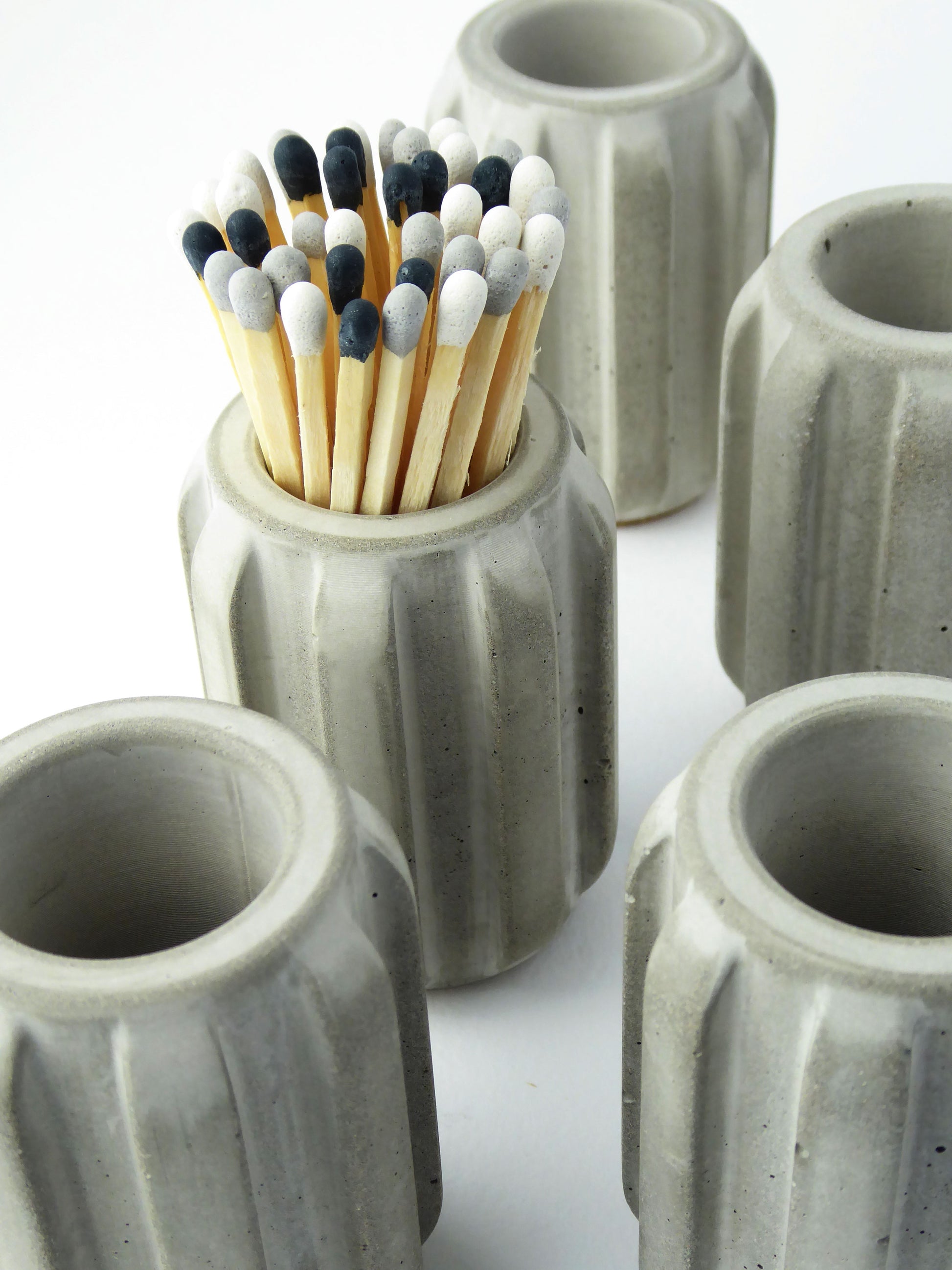 Grey concrete match stick holders with matches on a white background