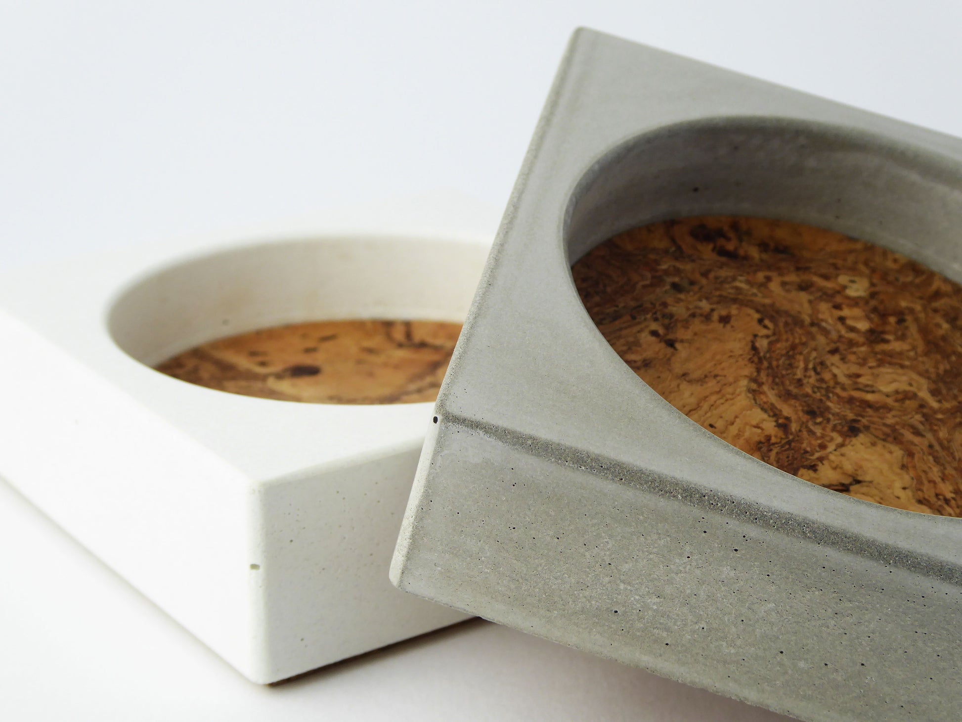 Two concrete trinket trays with marbled cork inserts on a white background
