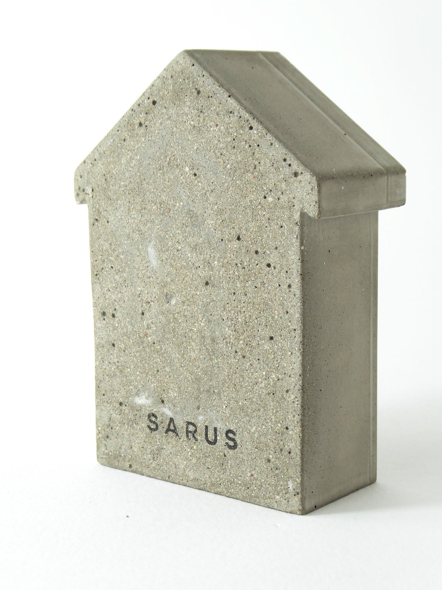 The back of a concrete beach hut with 'SARUS' logo imprinted
