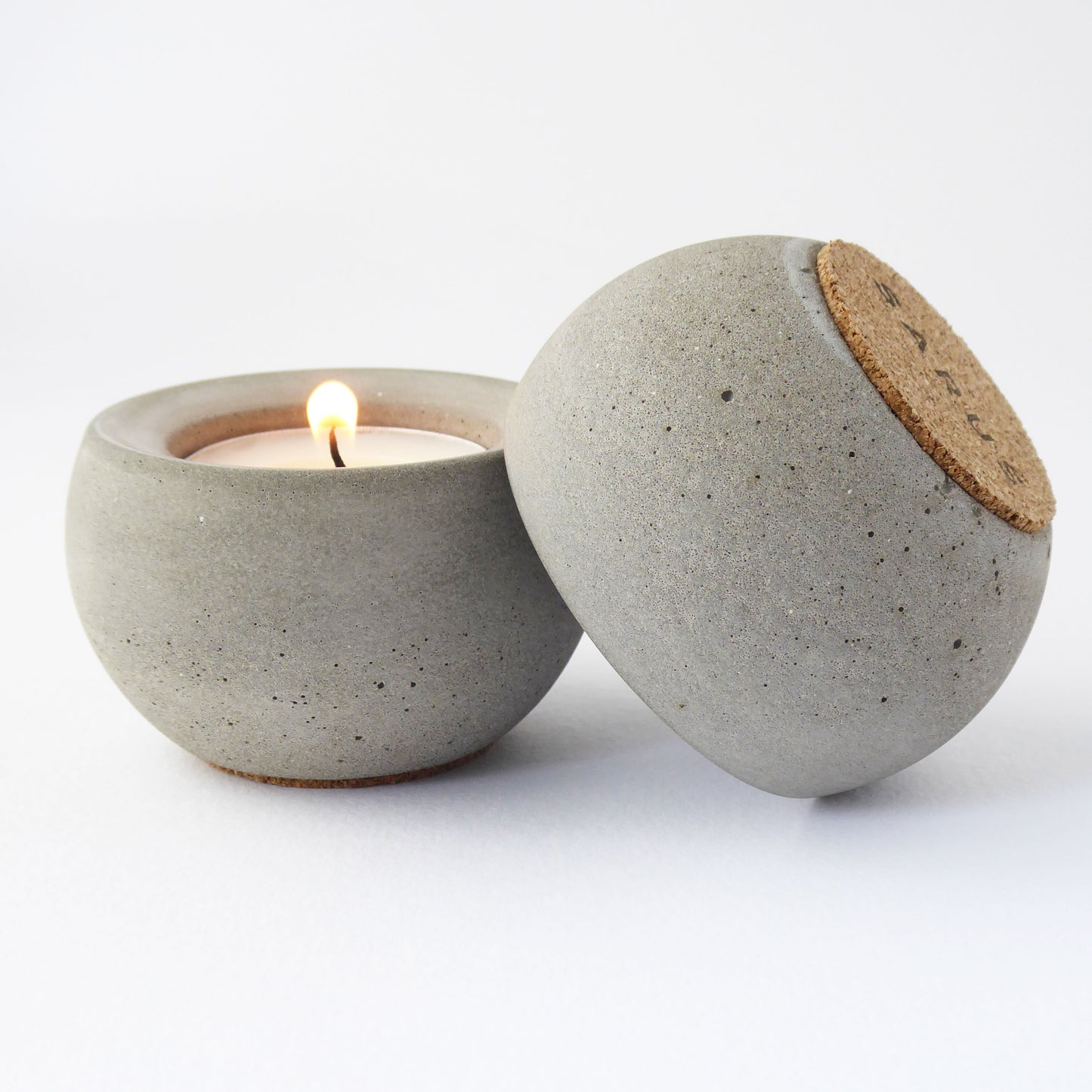 grey concrete candle holder with a lit candle on a white background