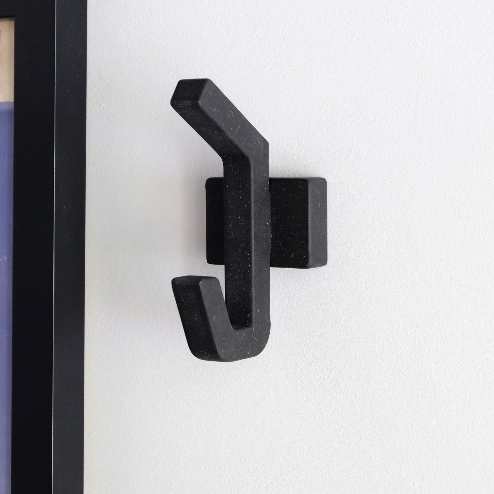 A handmade black wooden clothes hook on a white wall