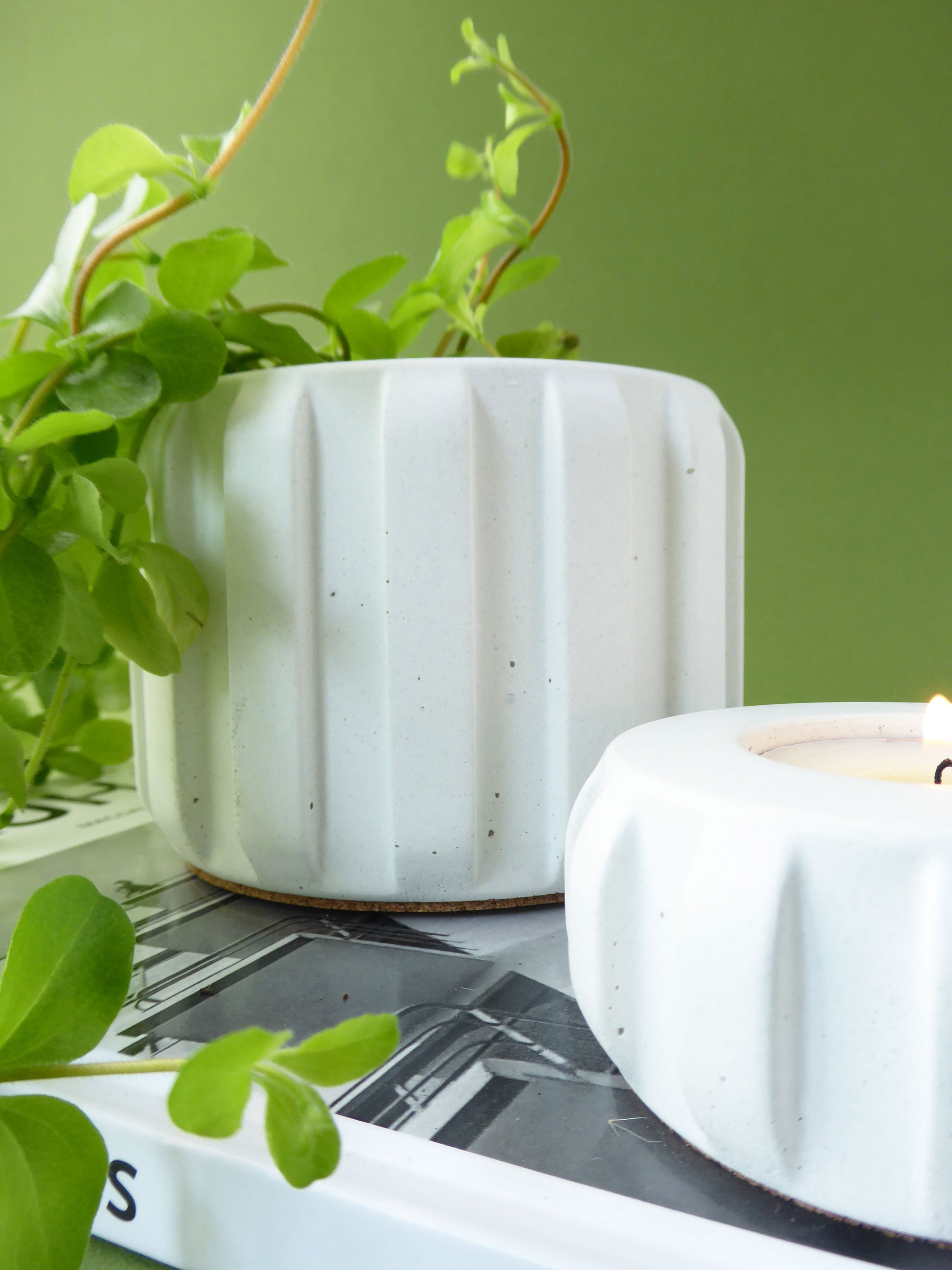 White ceramic plant pot with a unique ribbed design next to a matching candle holder.