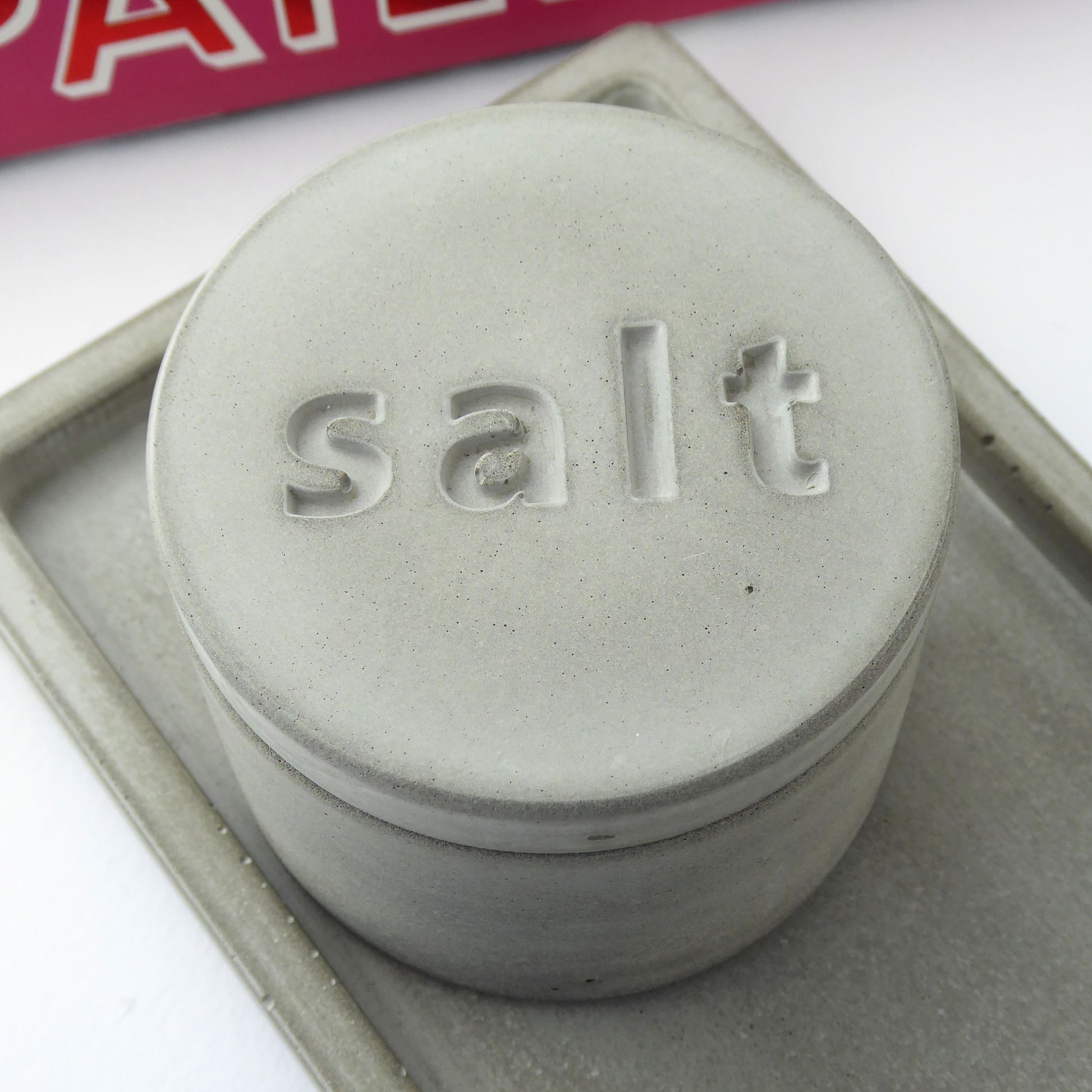 Natural gray salt container with 'salt' engraved on the lid on a white background