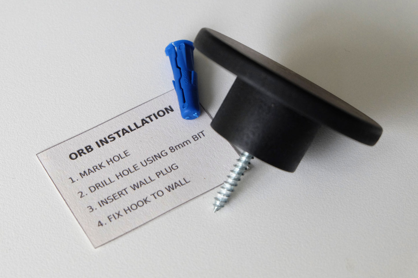 Modern black wall hook with mounting instructions and wall plug for easy installation