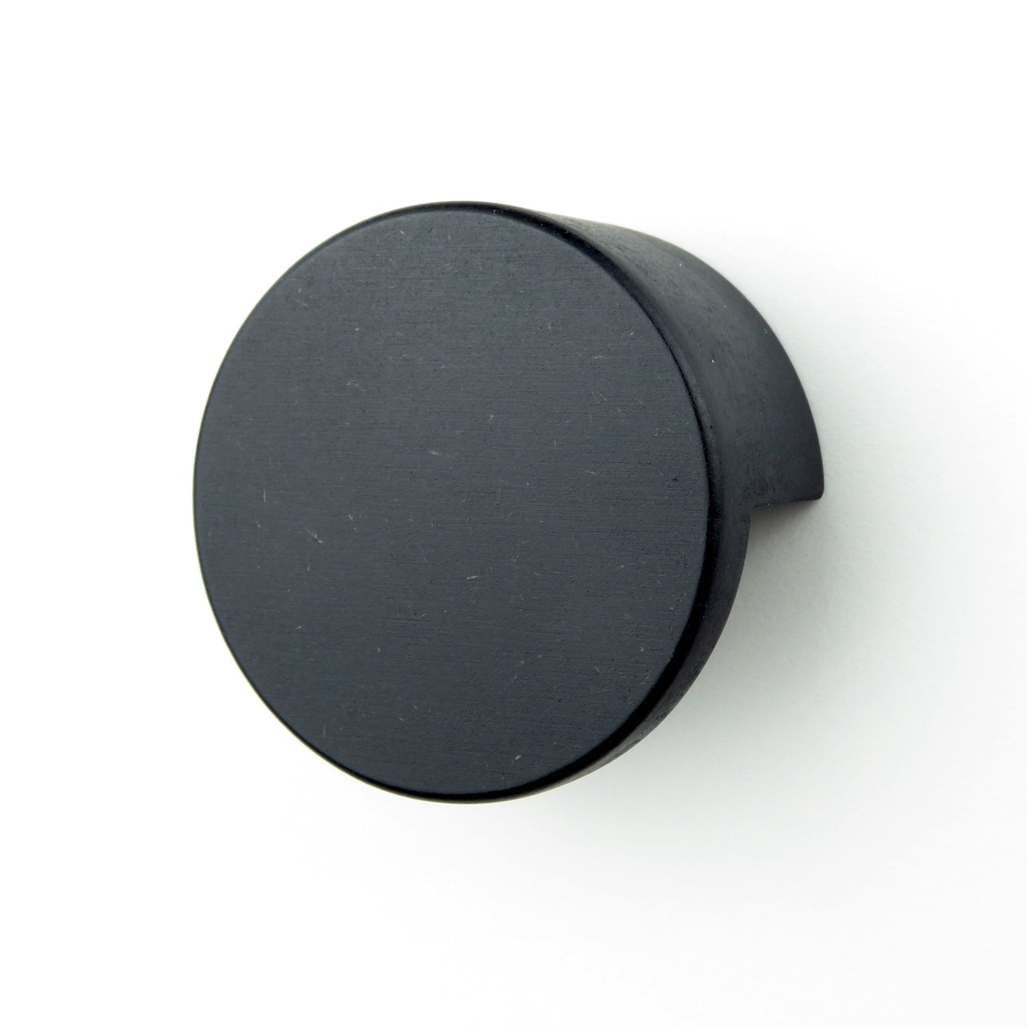 Modern round drawer knob in black wood on a white cupboard