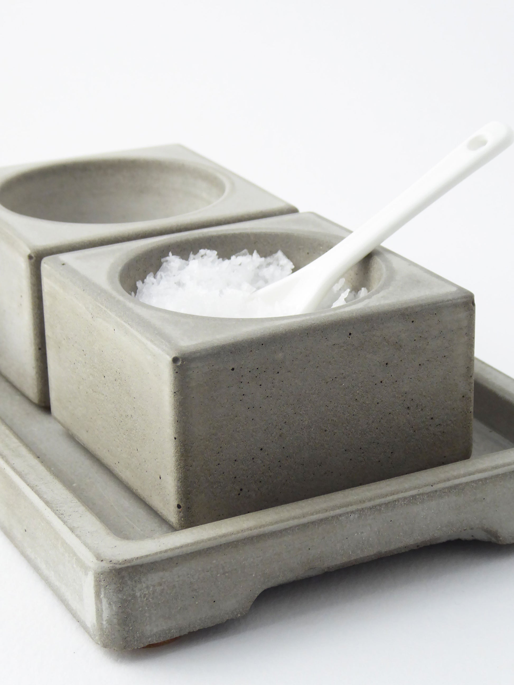 Two grey concrete salt and pepper dishes set on a white background
