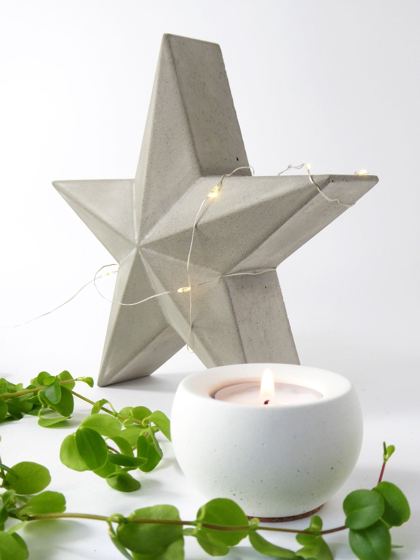 Decorative concrete amish barn star with string lights and a white candle on a light background