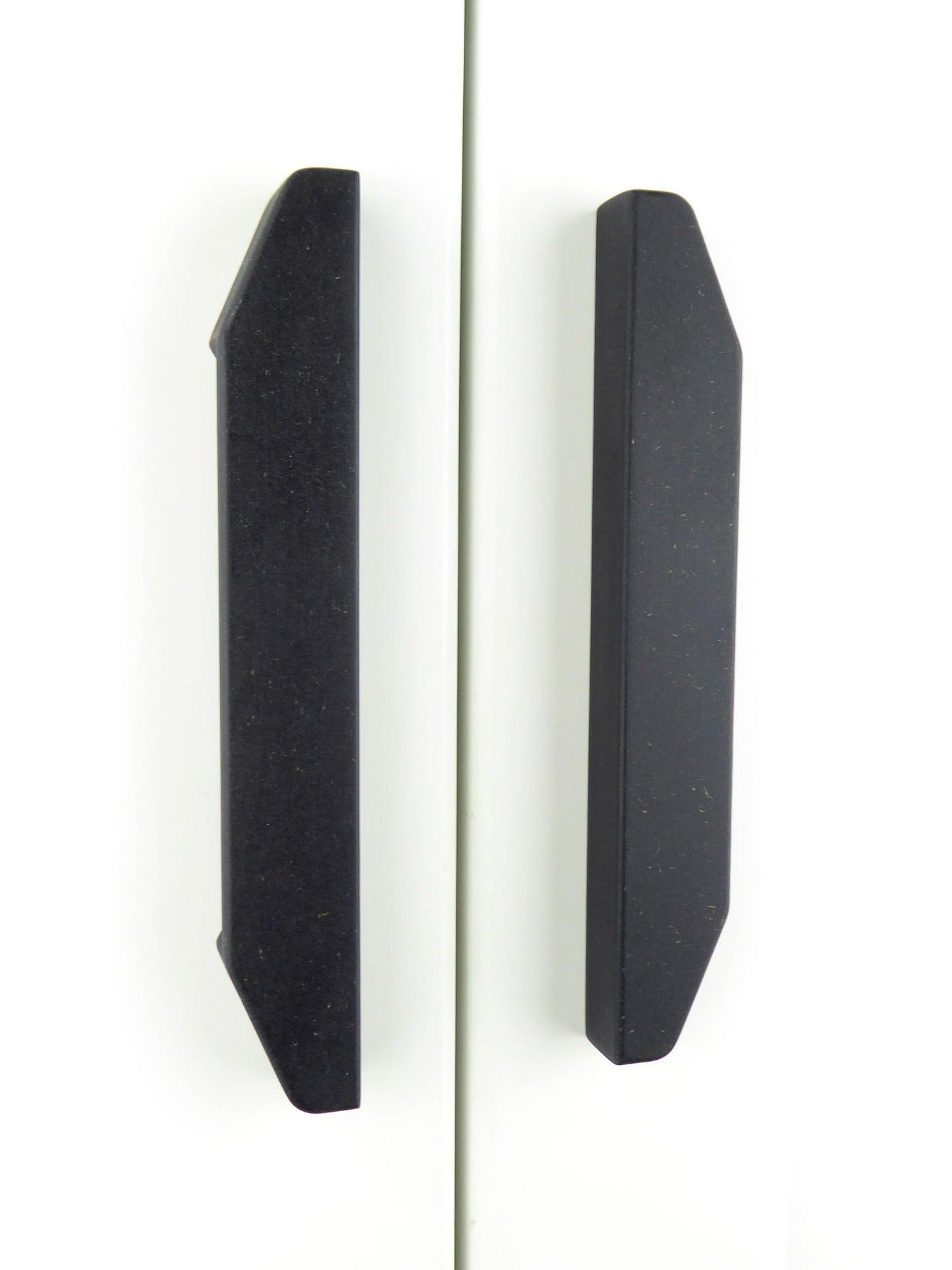 A pair of longline handmade wooden handles mounted on white cupboard doors