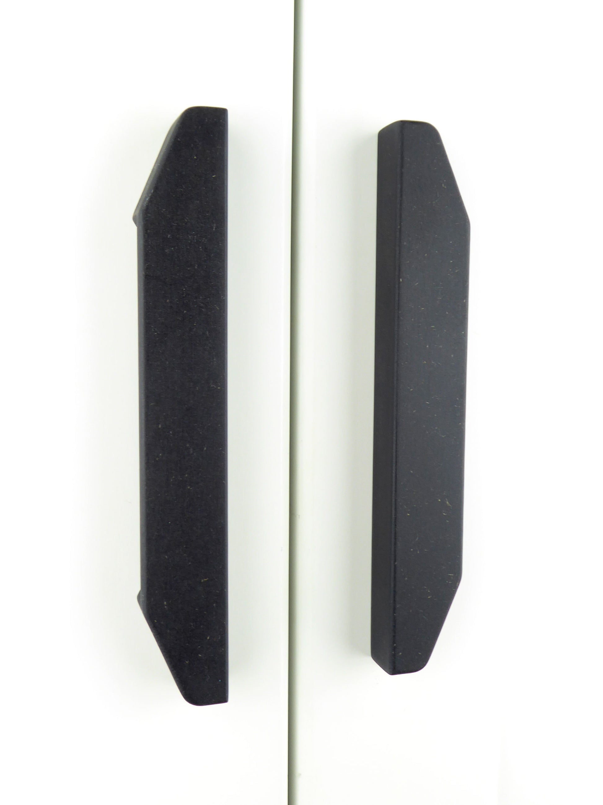 A pair of longline handmade wooden handles mounted on white cupboard doors