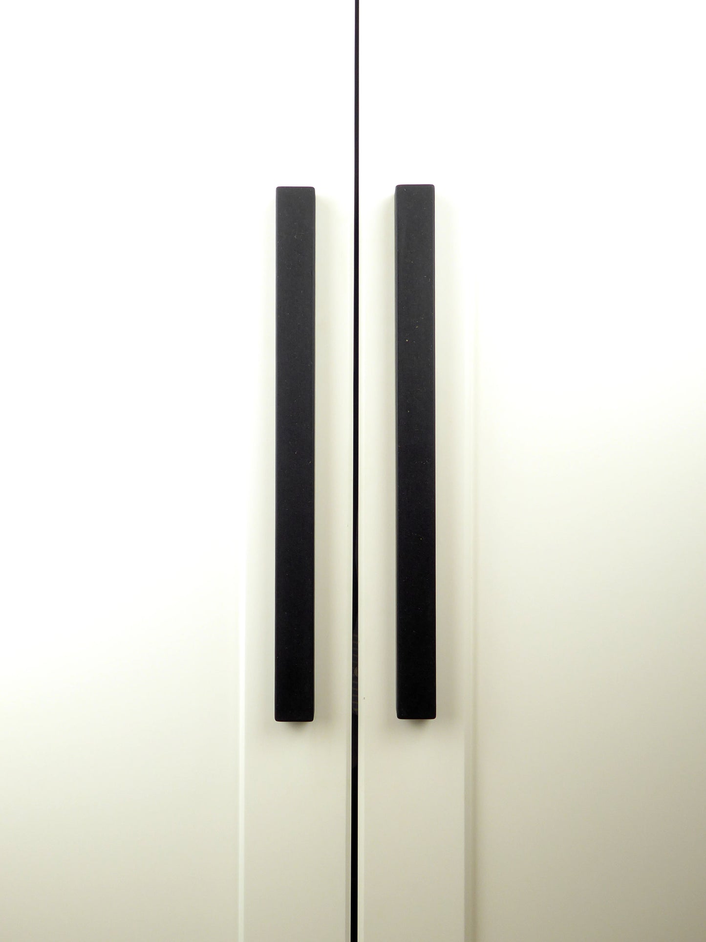 Pair of long black cupboard handles mounted on a kitchen cabinet