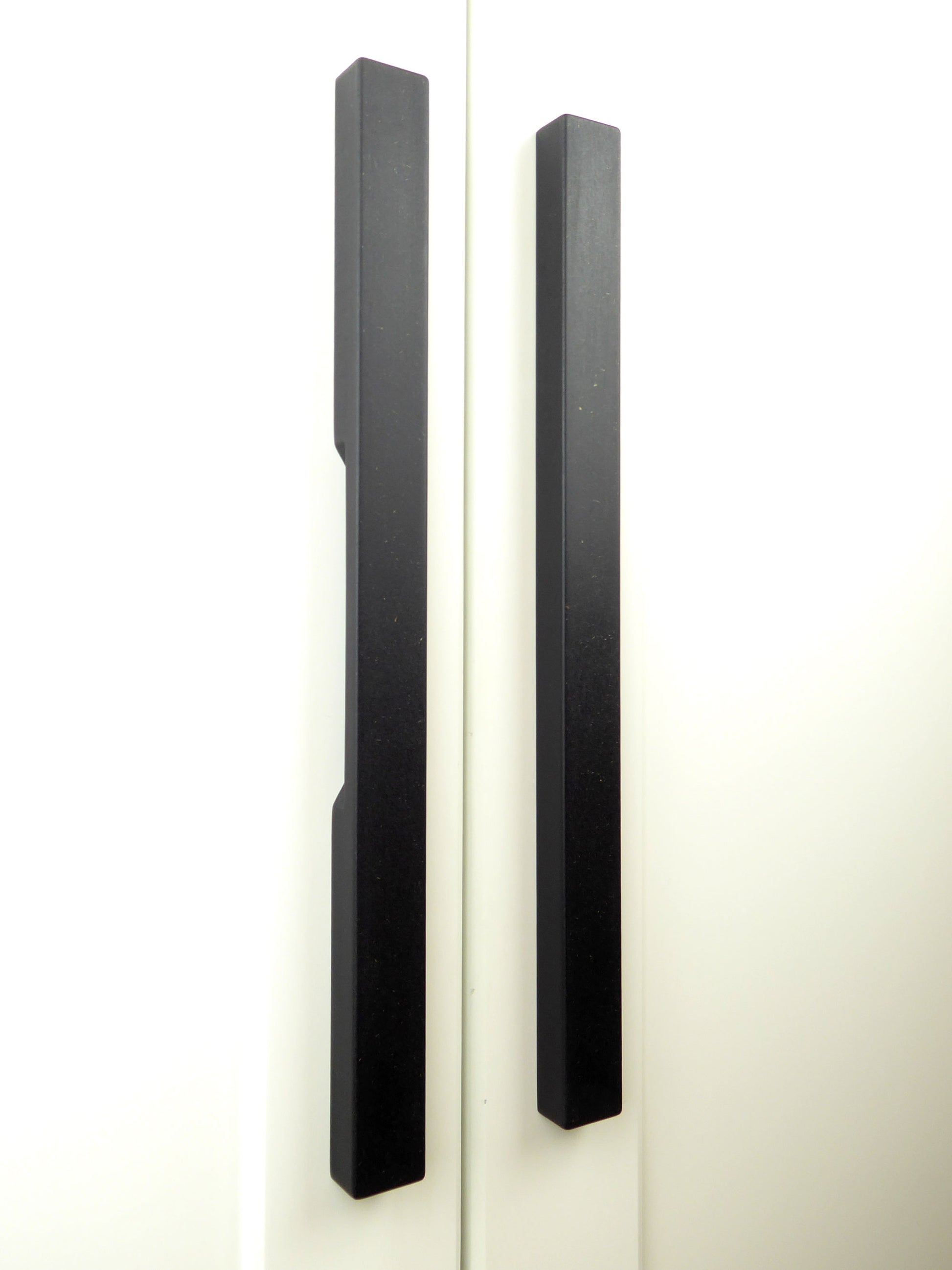 pair of black handmade wooden door pulls mounted on wardrobe doors