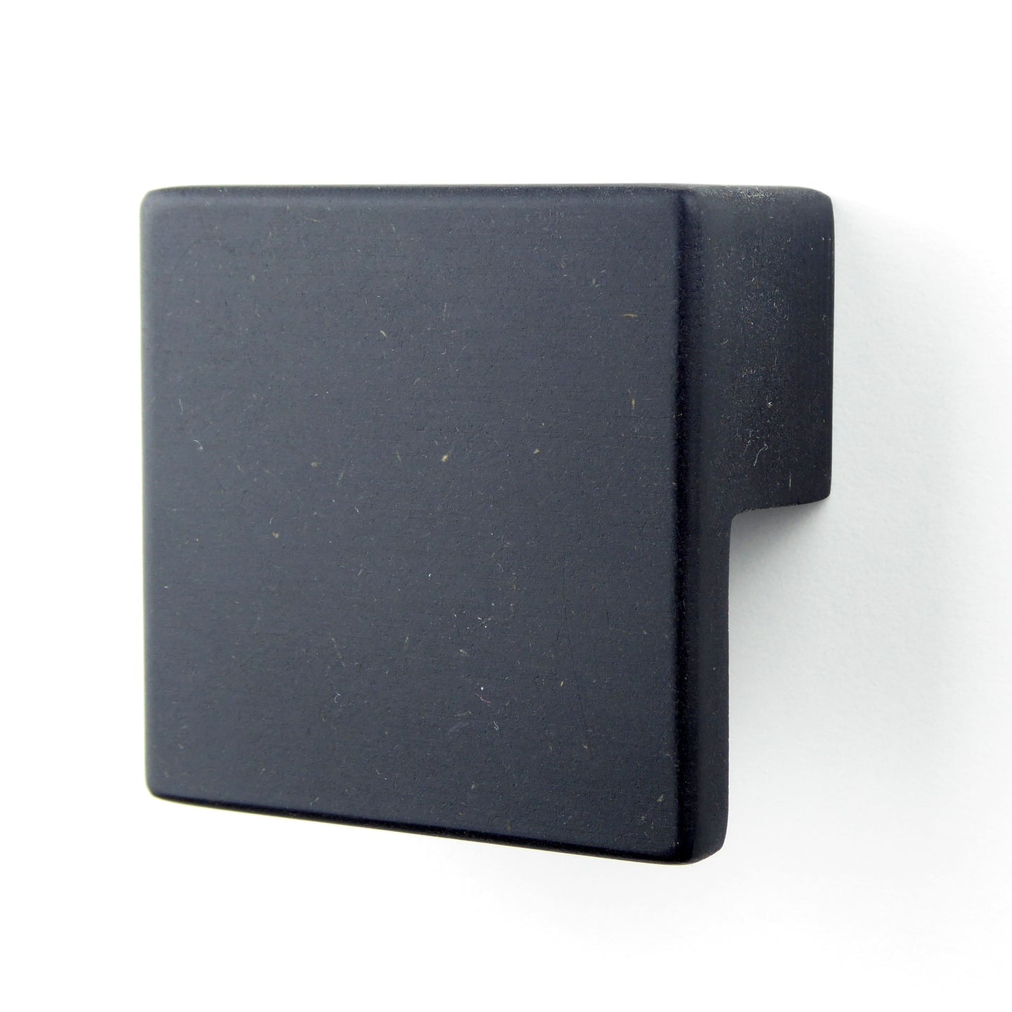 A black square wooden drawer pull handle mounted on a white cabinet