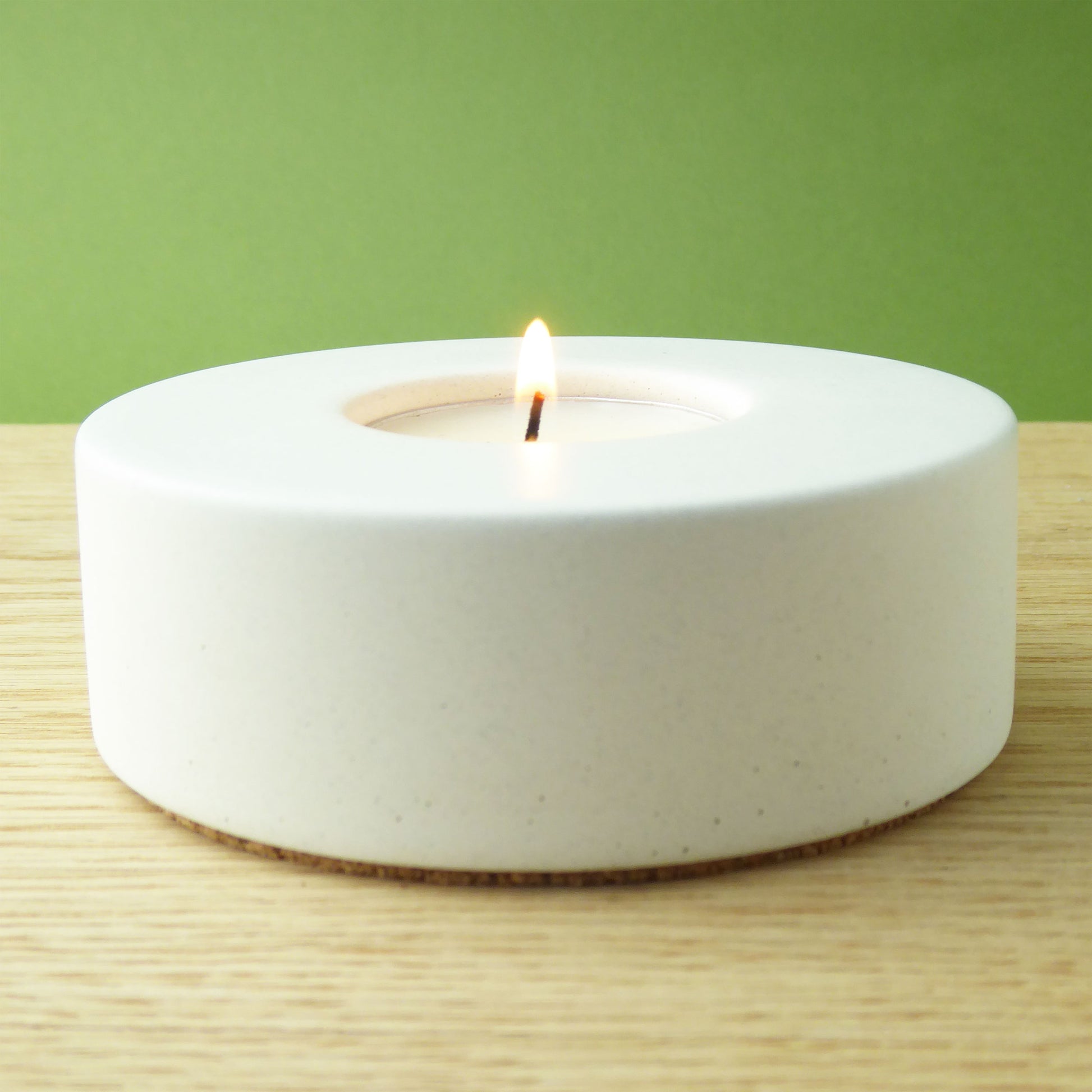White candle in a modern white holder on a wooden shelf