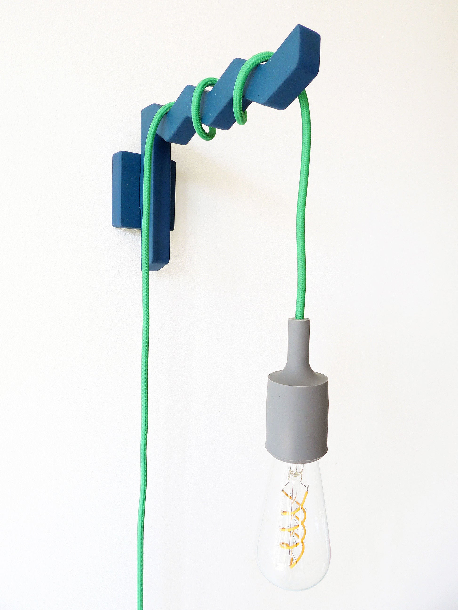 Modern wall-mounted light fixture with green light cable wrapped around it