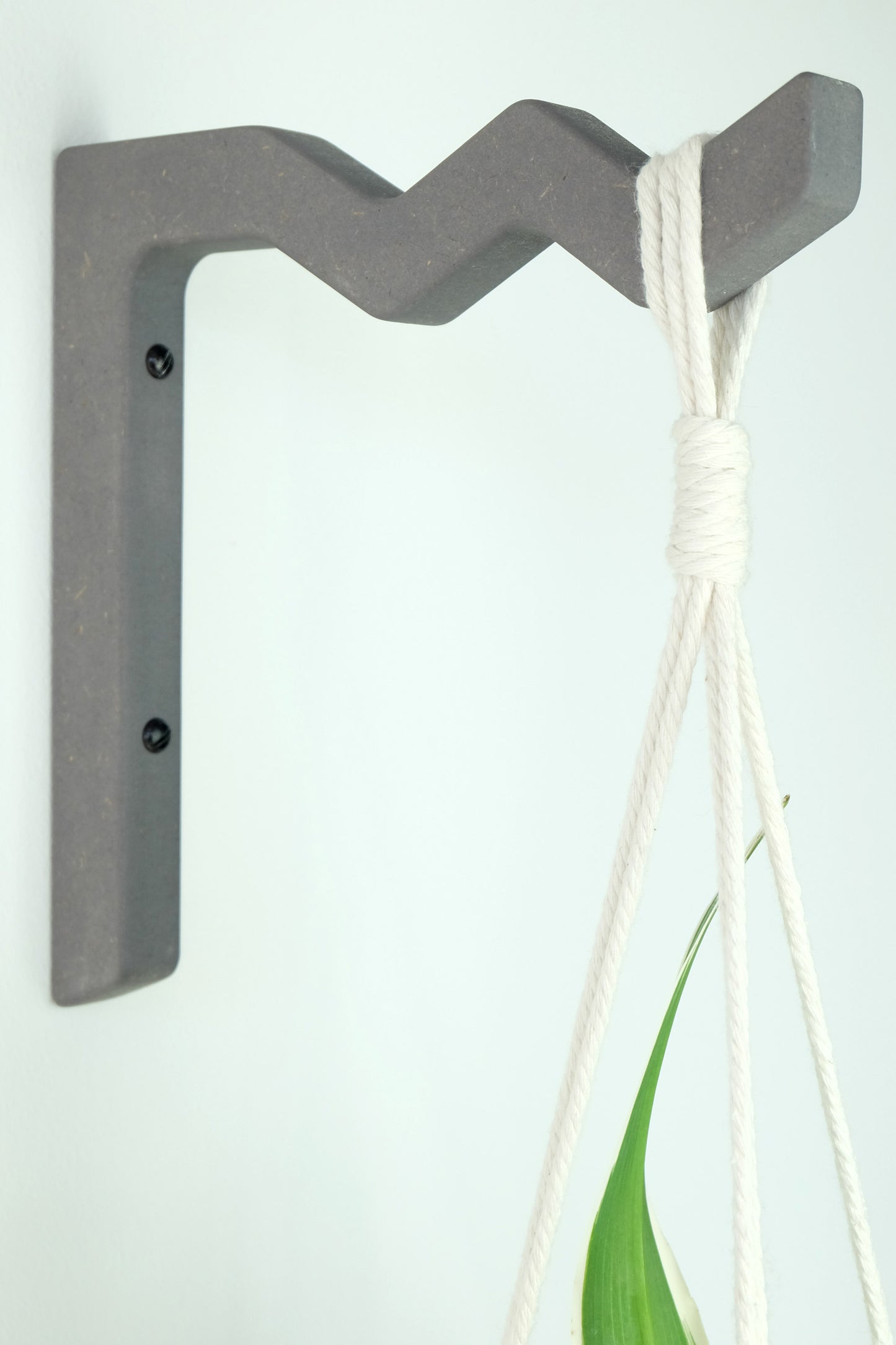 Zig zag shaped wooden wall hook in grey with a white macrame plant hanger