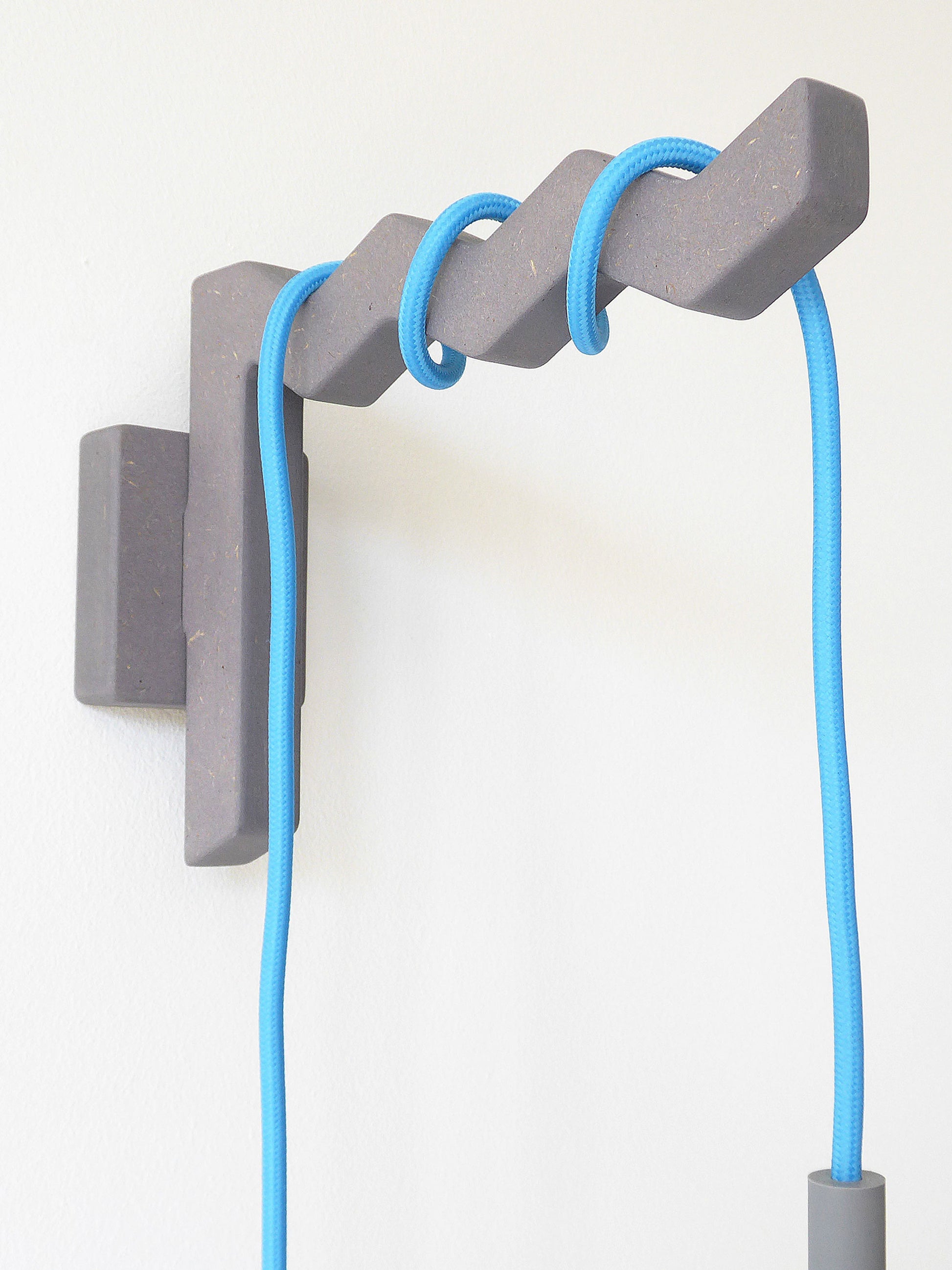 Gray wall-mounted hook with a blue plug in pendant light cable on a white background