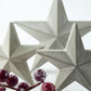 Three star-shaped decorative ornaments with a branch of red festive berries in the foreground.