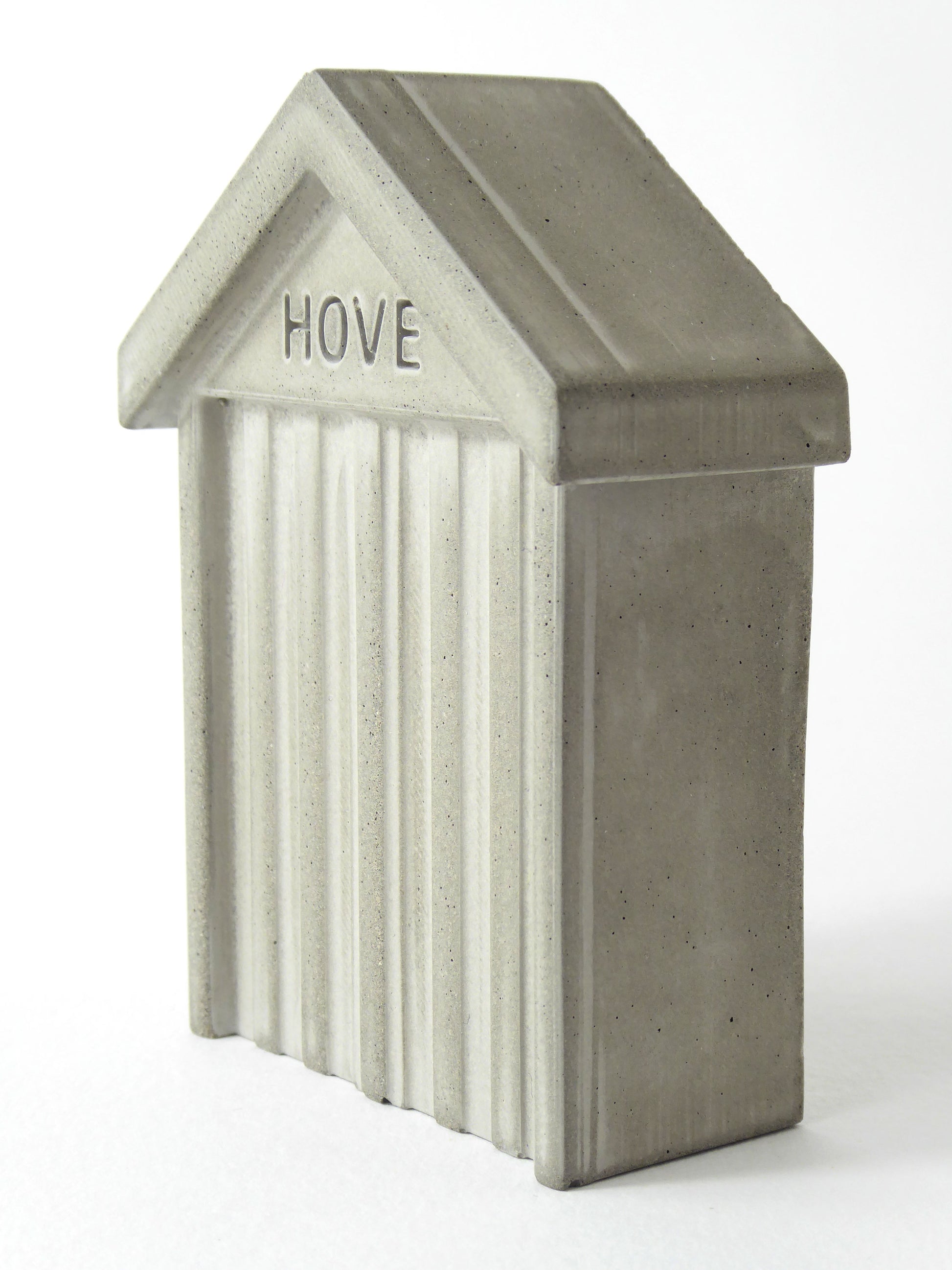 Small grey concrete beach hut with 'HOVE' embossed in the design on a white background
