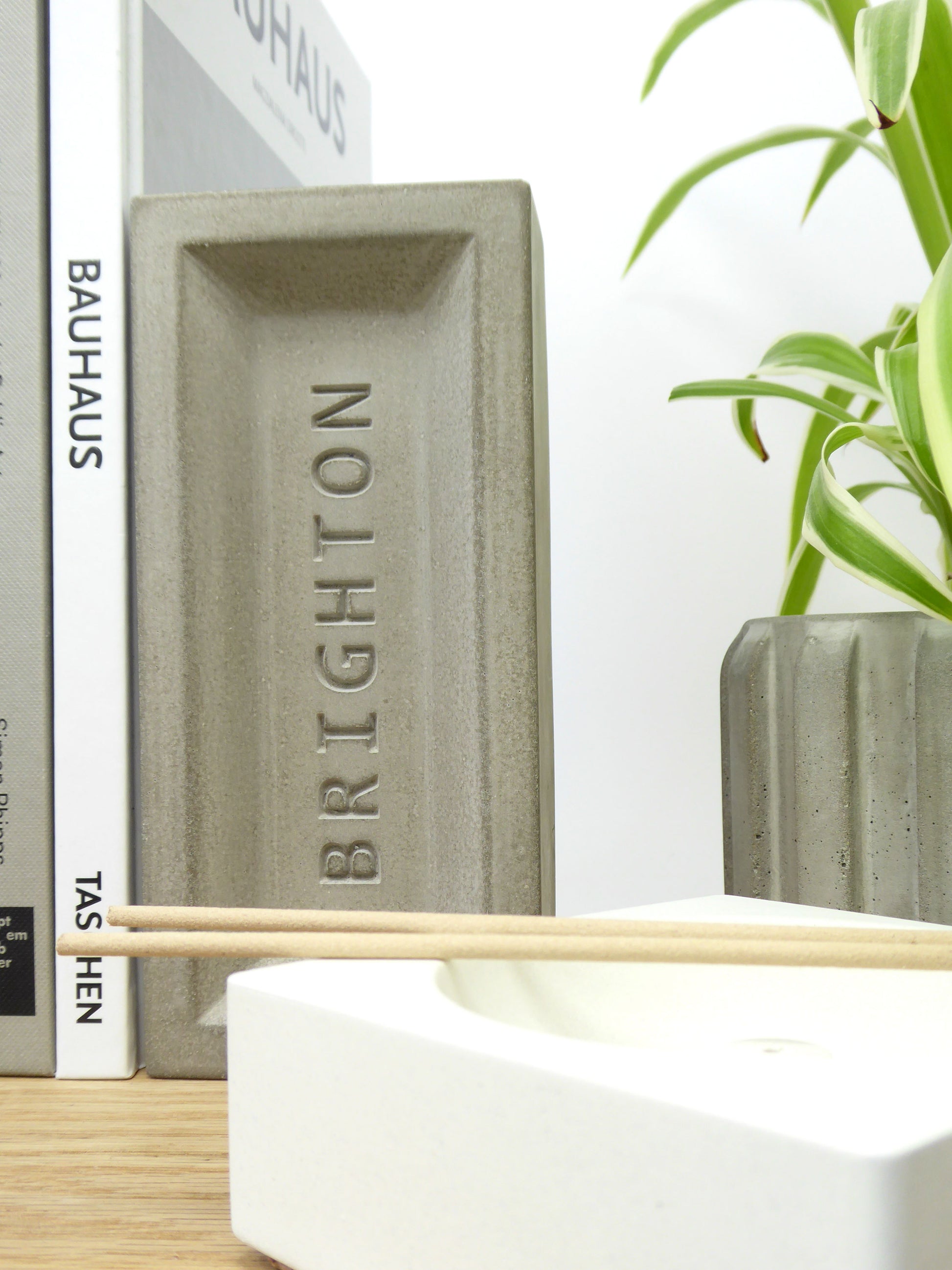 Concrete brick with 'Brighton' engraved propping up books on a shelf 
