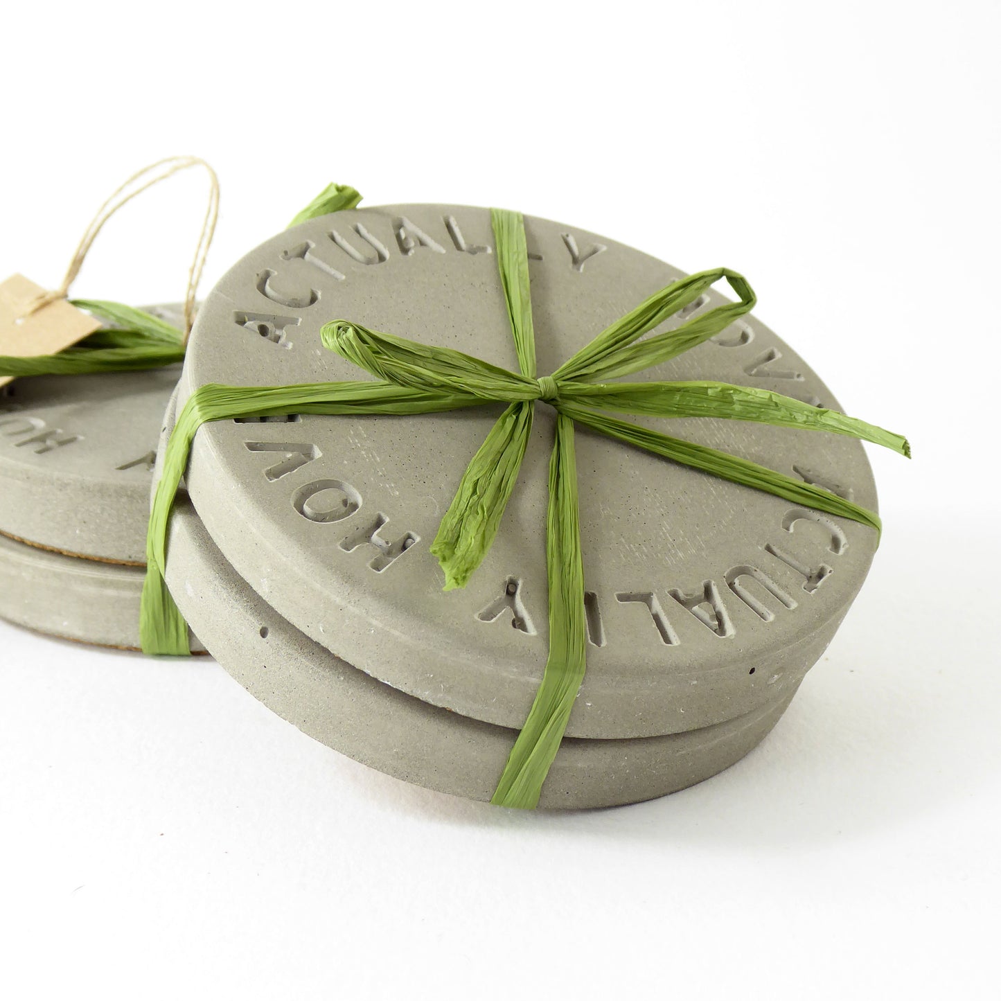 Set of raw concrete coasters with 'Hove Actually' embossed in the design, wrapped with raffia for gifting