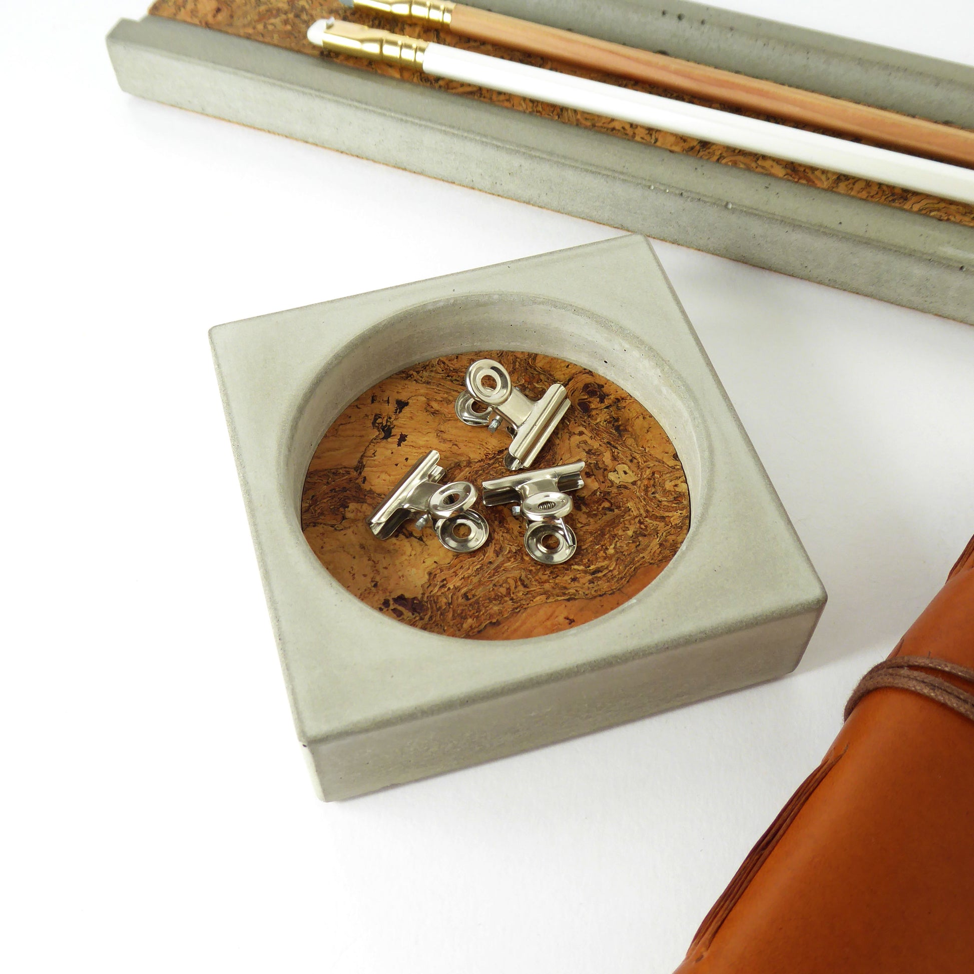 Grey concrete tray with a natural cork insert containly desk accessories 