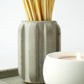 Concrete match holder with long matches next to a lit candle on a concrete tray