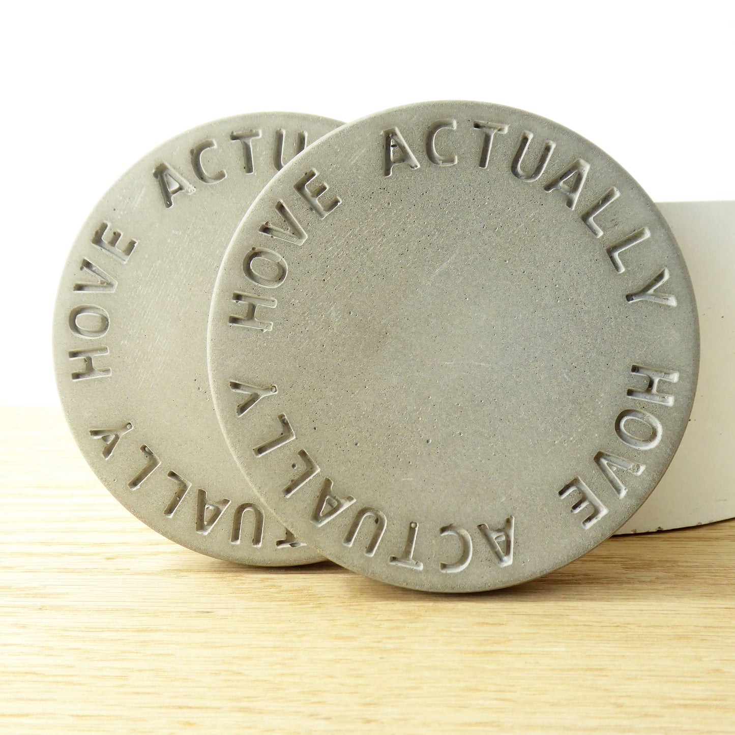 Close-up of a round concrete coaster with Hove Actually embossed