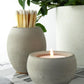 Grey concrete pot with long matches and alongside a matching concrete candle holder with lit candle