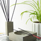 Concrete incense stick holder with black incense sticks and a matching grey pot containing incense sticks