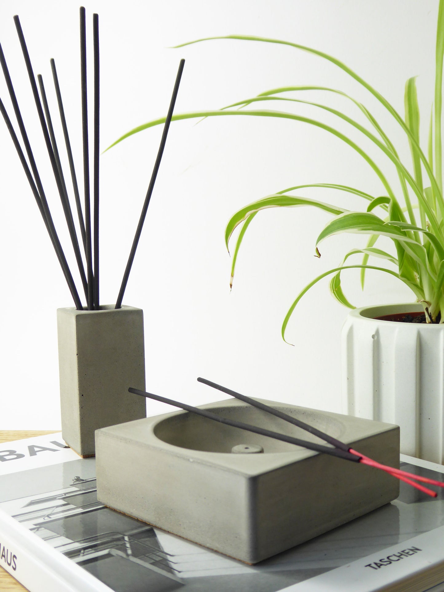 Concrete incense stick holder with black incense sticks and a matching grey pot containing incense sticks