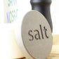 Close-up of an engraved grey wooden lid of a concrete salt pot showing the word 'salt'