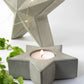 Concrete star-shaped candle holder with a lit candle on a white background