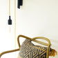 wall-mounted lamp hook with a yellow cord pendant light wrapped around the arm positioned as a reading light above a chair