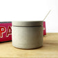 raw concrete pot with lid and white spoon a kitchen worktop with cookbooks