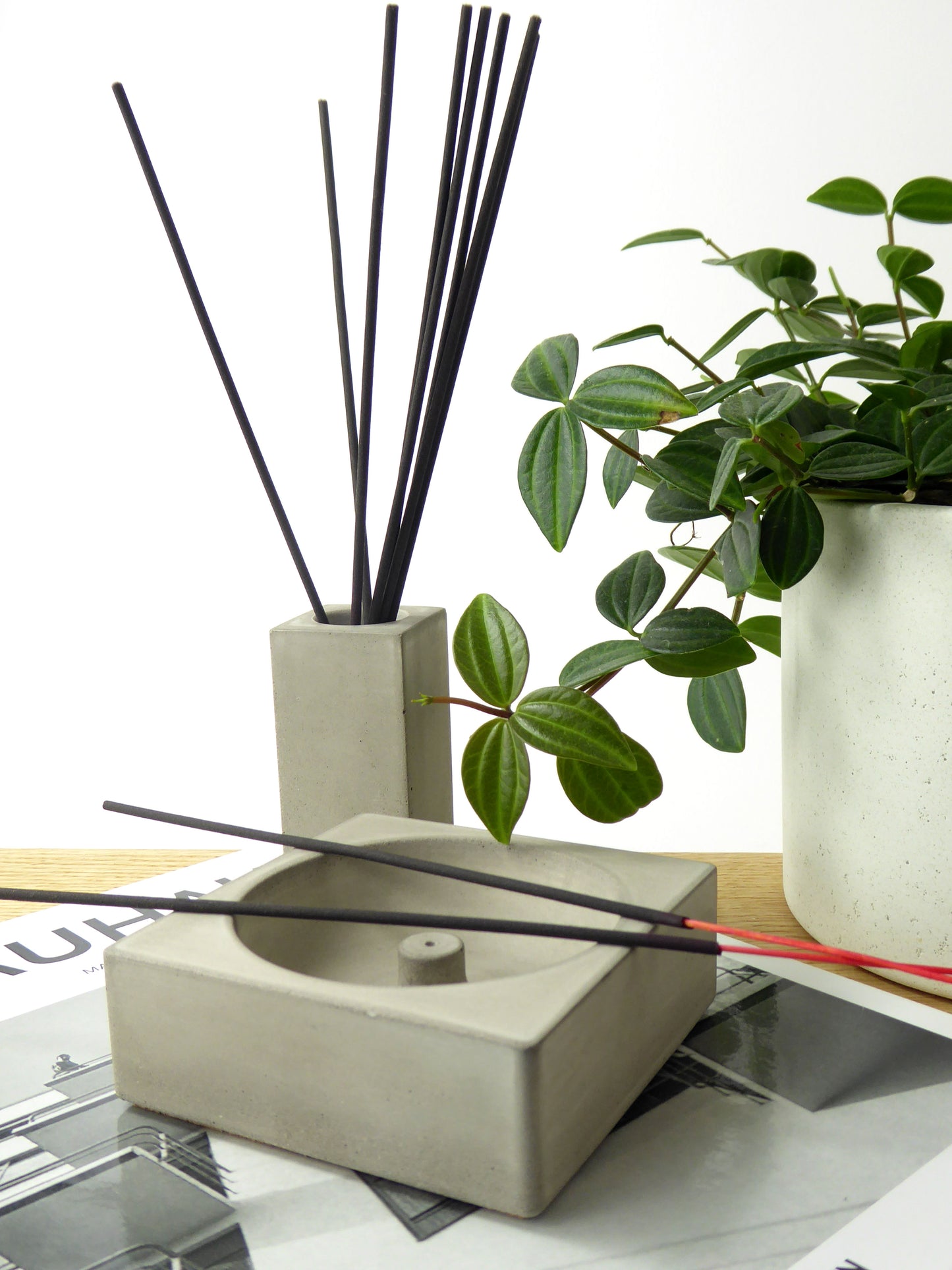 Concrete joss stick holder with black incense sticks with a matching pot holding more incense sticks